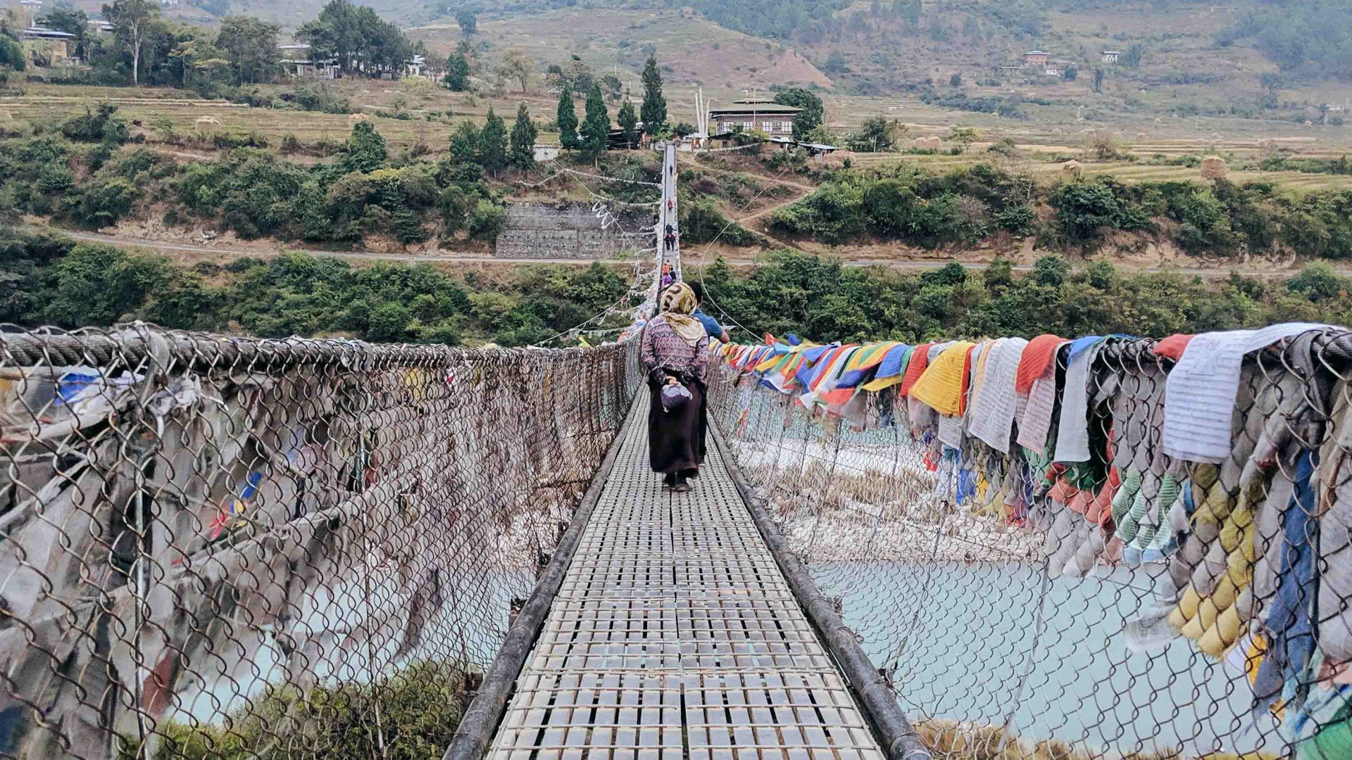 A suspension bridge covered in prayer flags.