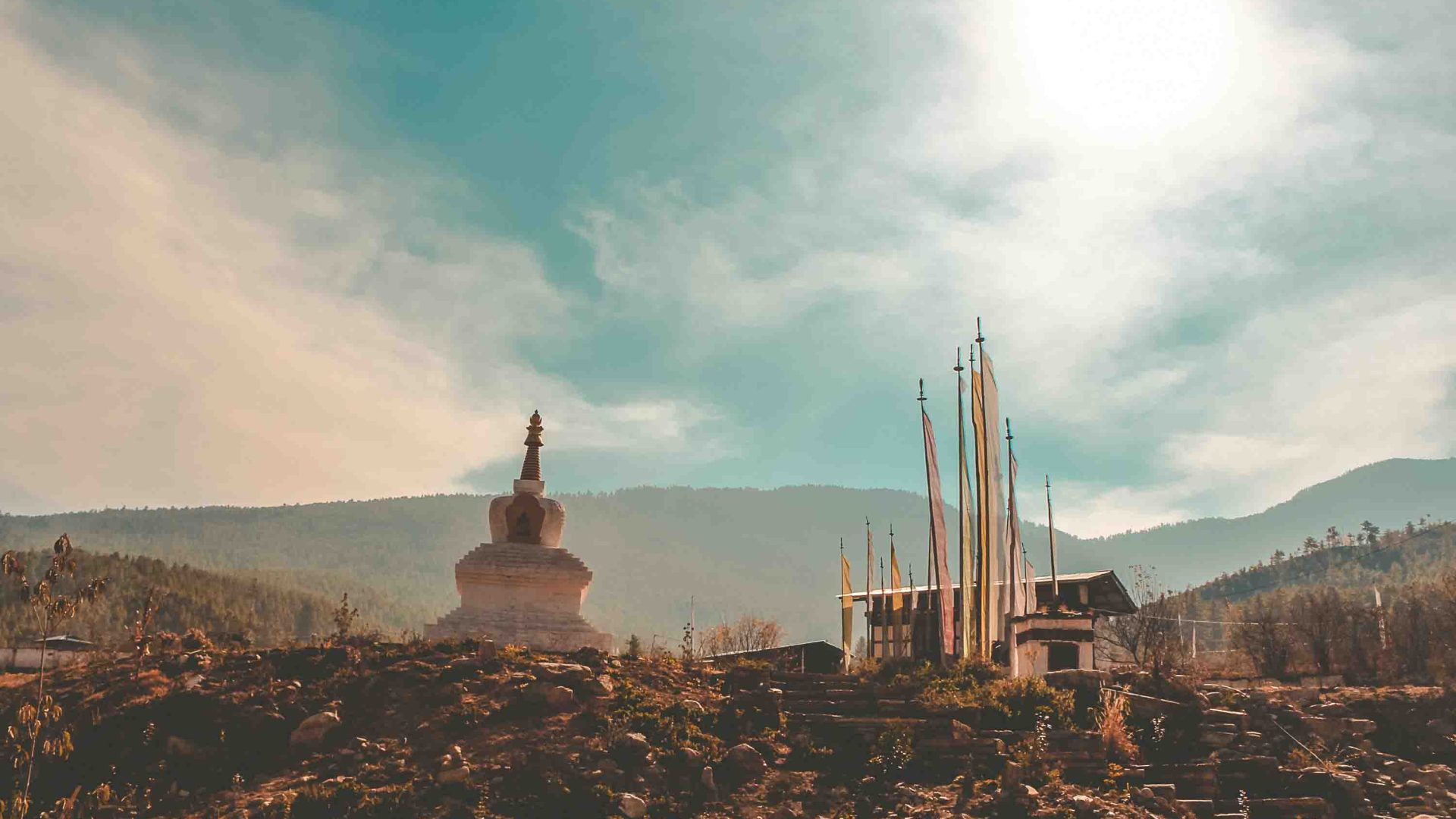 A small temple and flags in soft light on a hill.