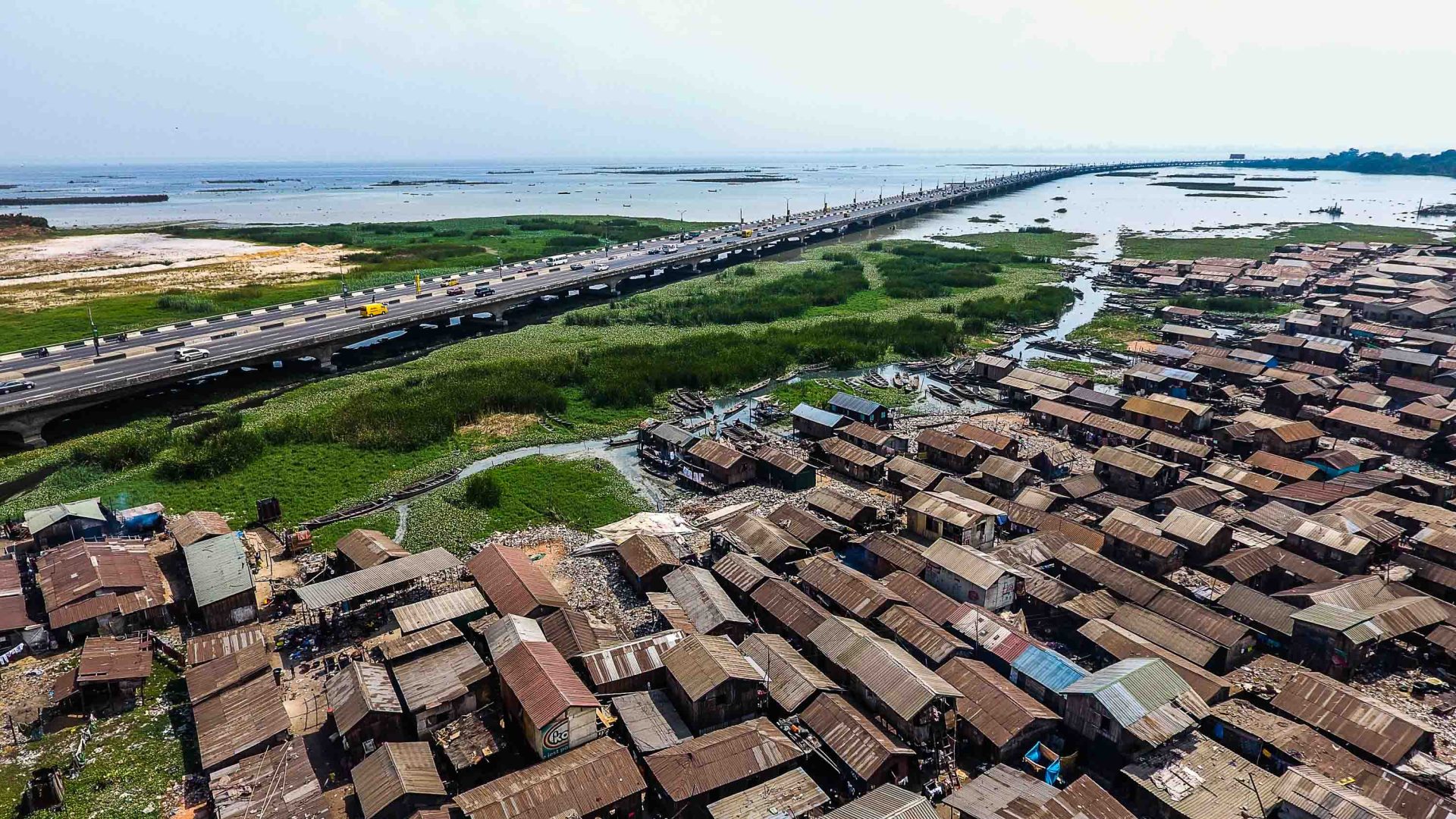 An aerial view of houses on waterways, alongside grass and a road.