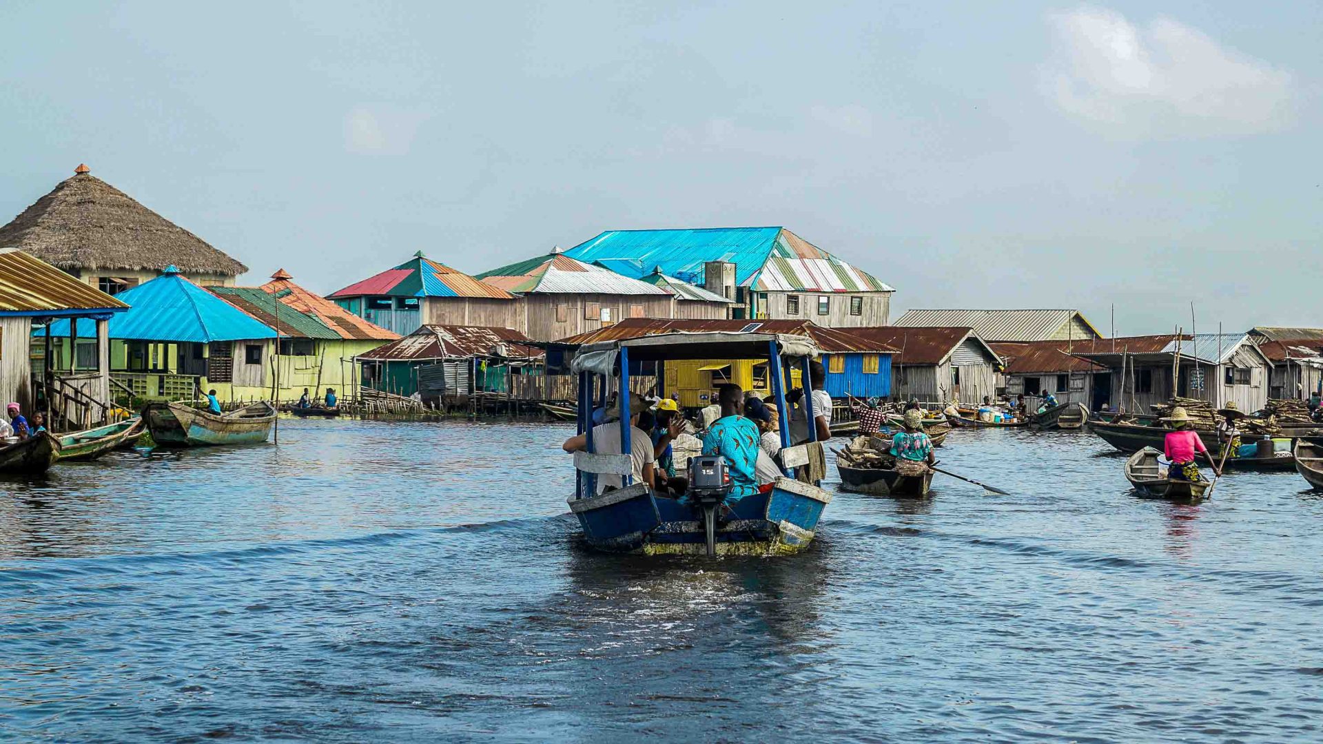 A boat with people passes through a floating village.