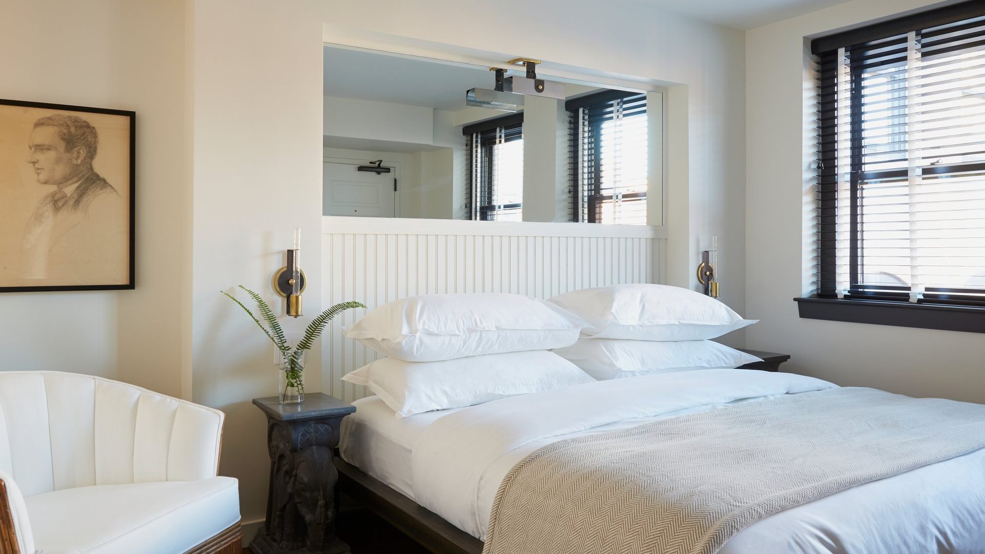 A hotel room at The Dean in downtown Providence, RI, with a bed with white sheets and a white armchair