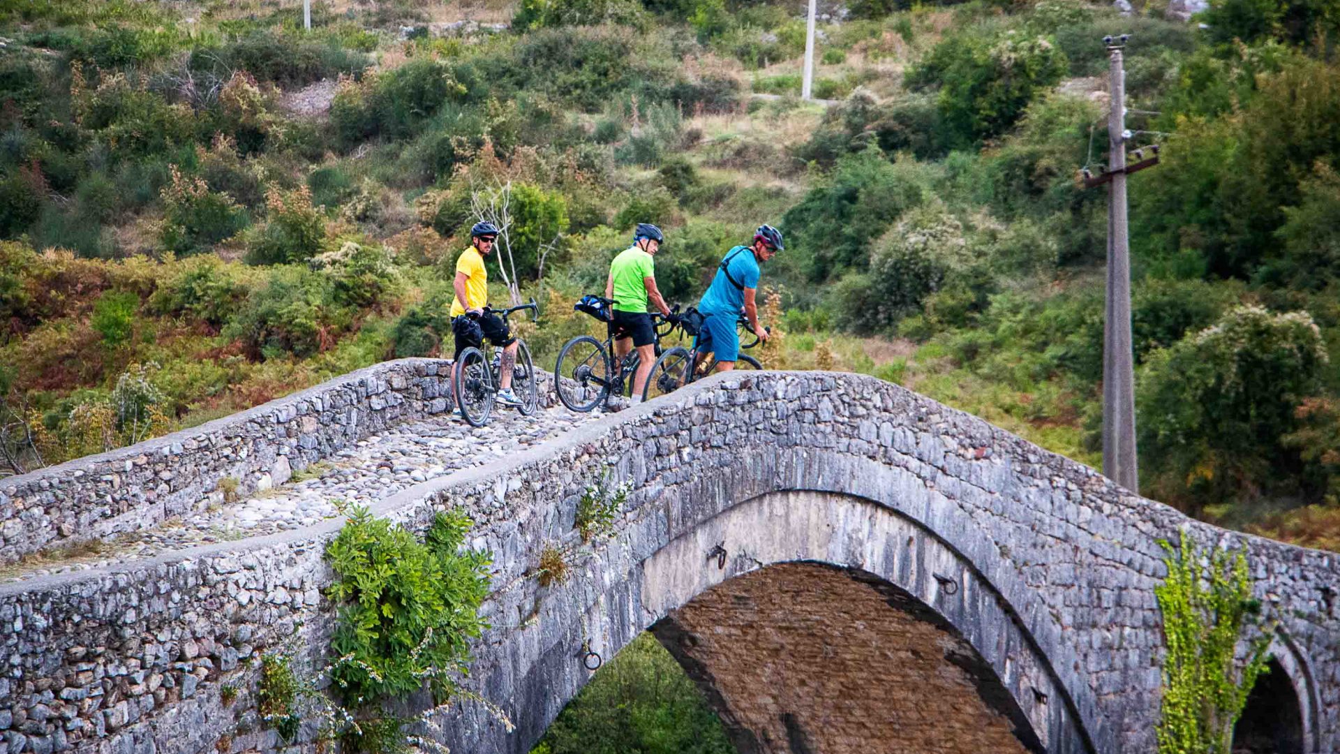 Three cyclists on a bridge.