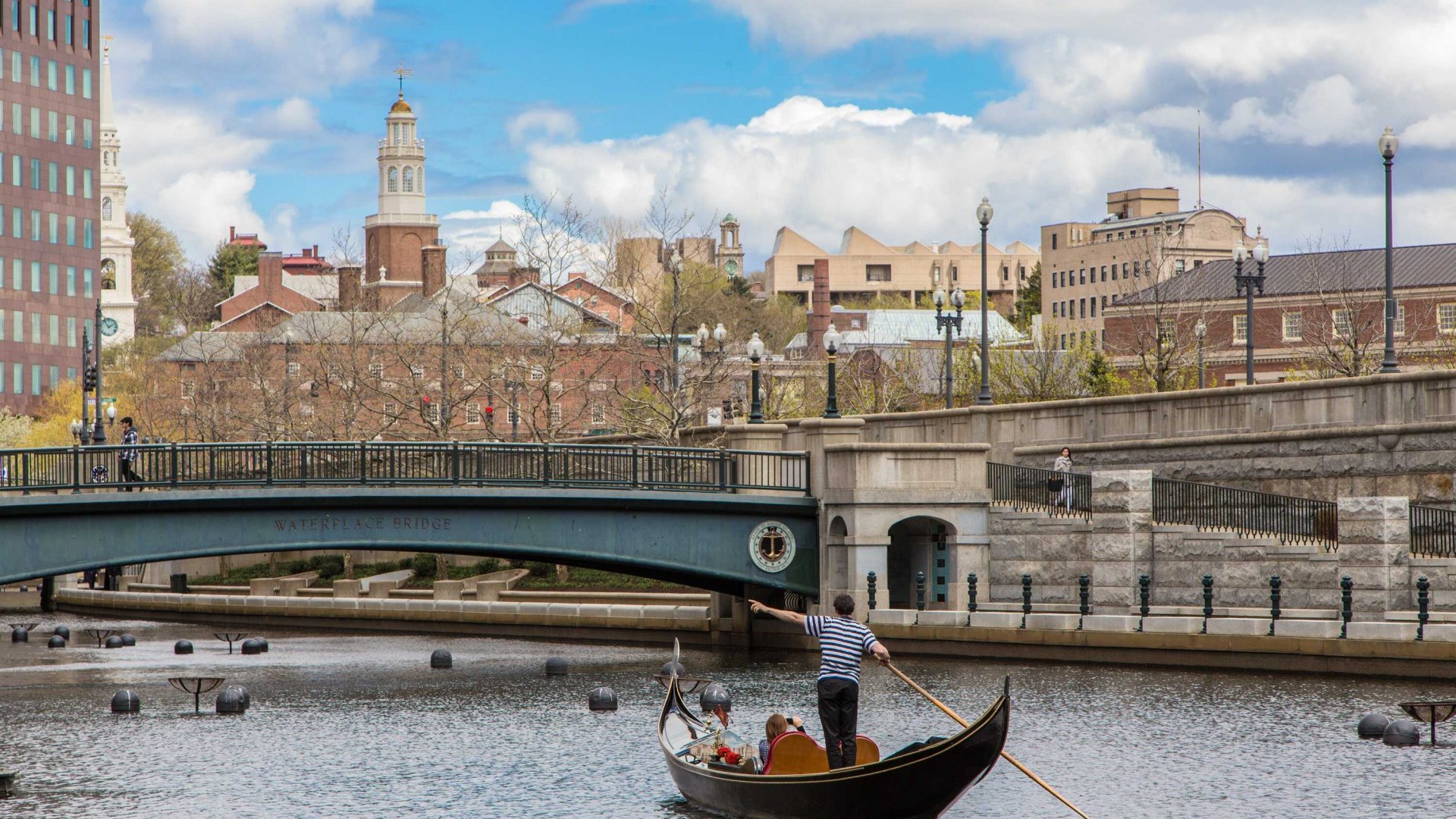 A person navigates a Venetian gondola through the water in Providence, Rhode Island.