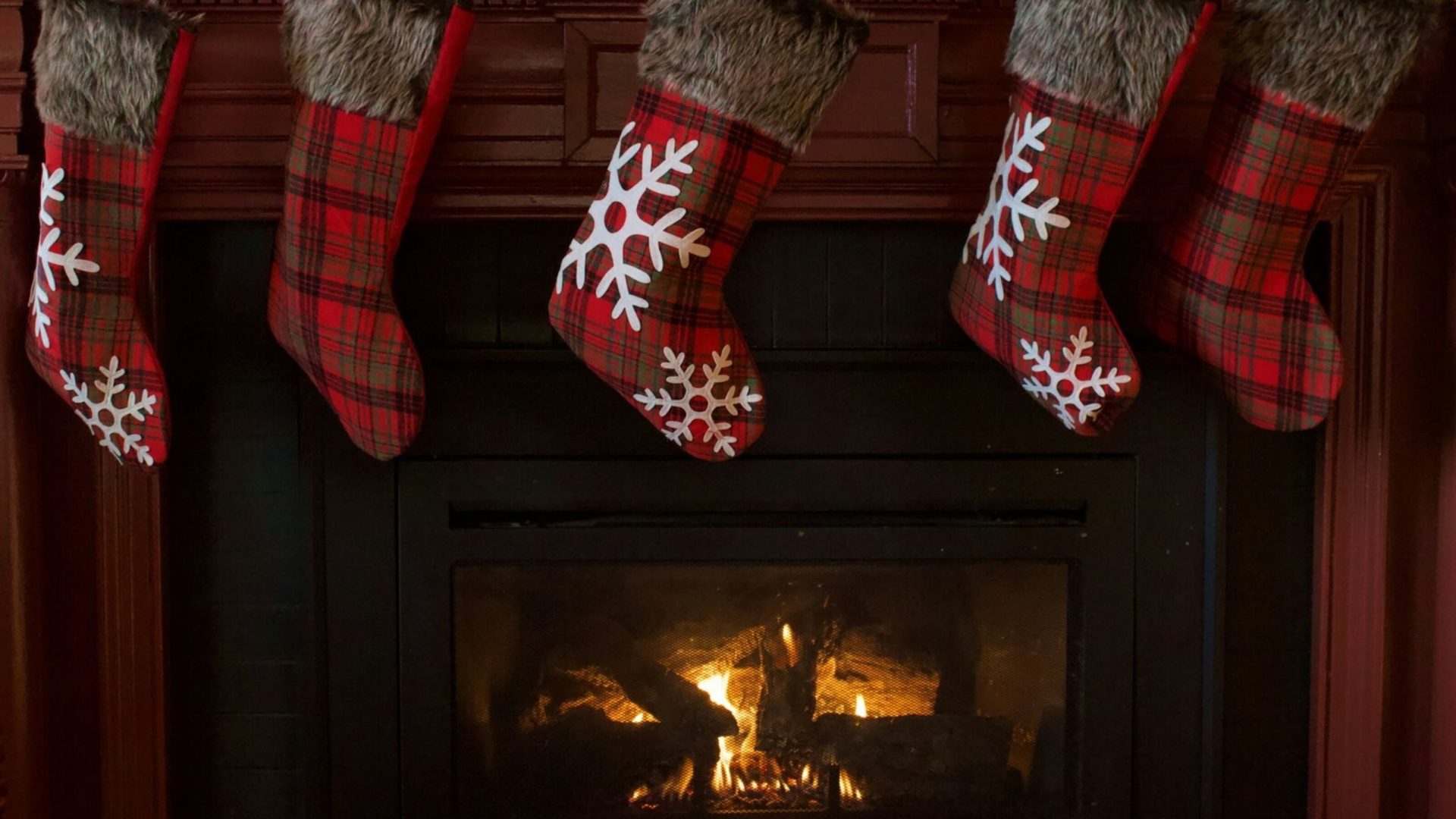 Red holiday stockings hang from the mantle above a cozy fire.