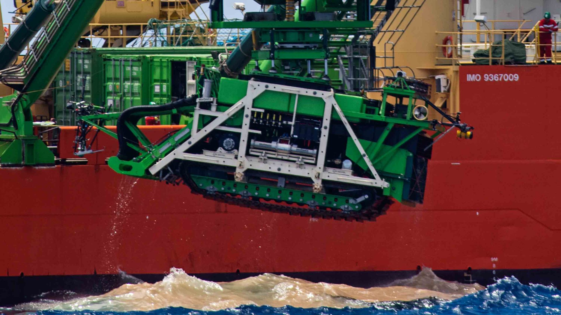 Dedged up brown water on the top of the sea, alongside a ship.