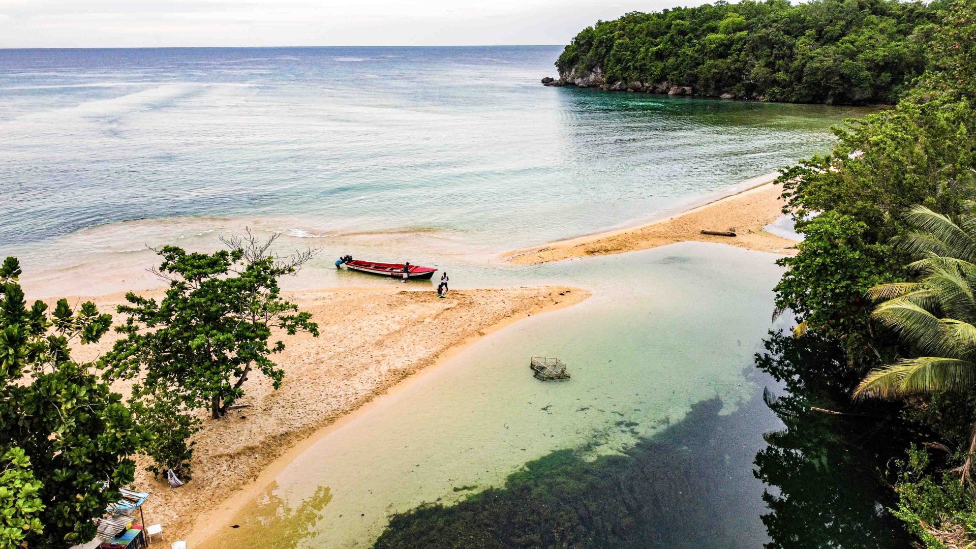 A beach and lagoon with a couple of boats on the sand.