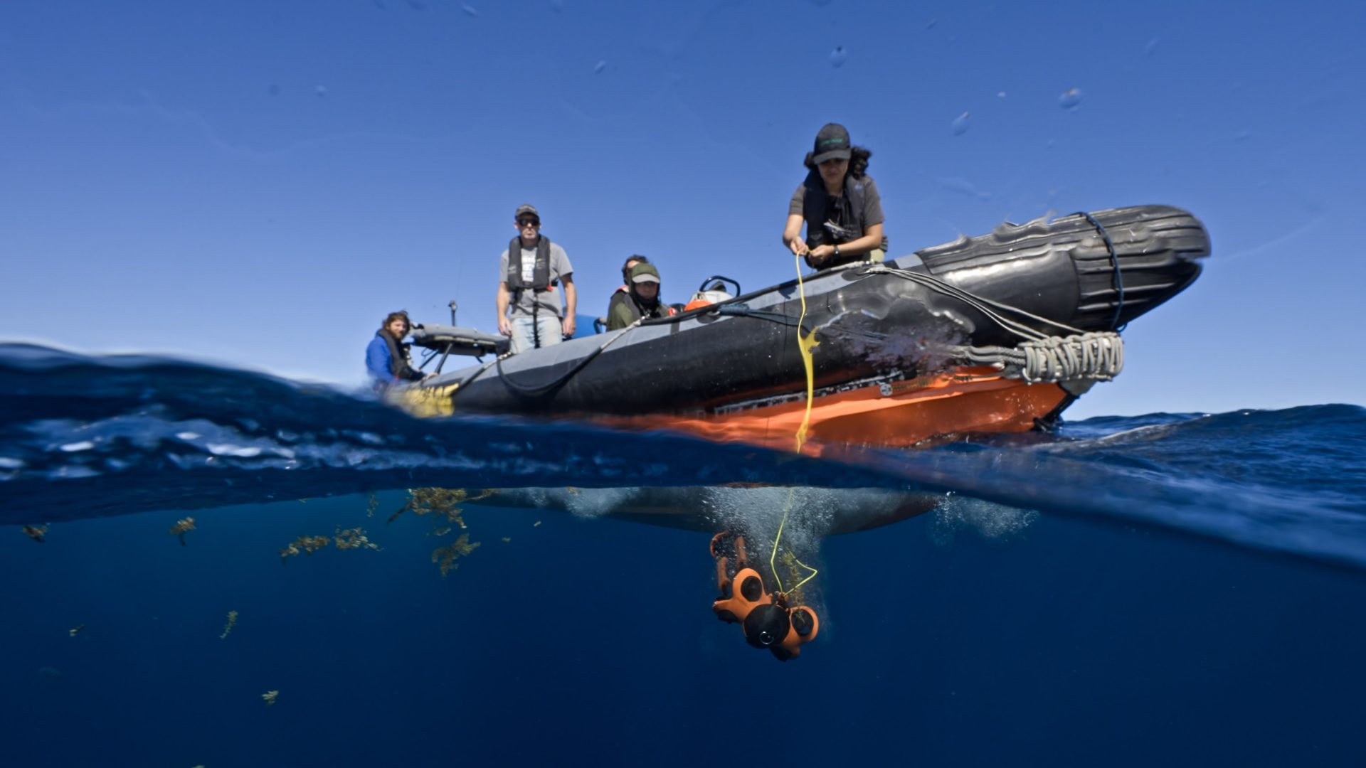 A drone is lowered into the water from a small boat.