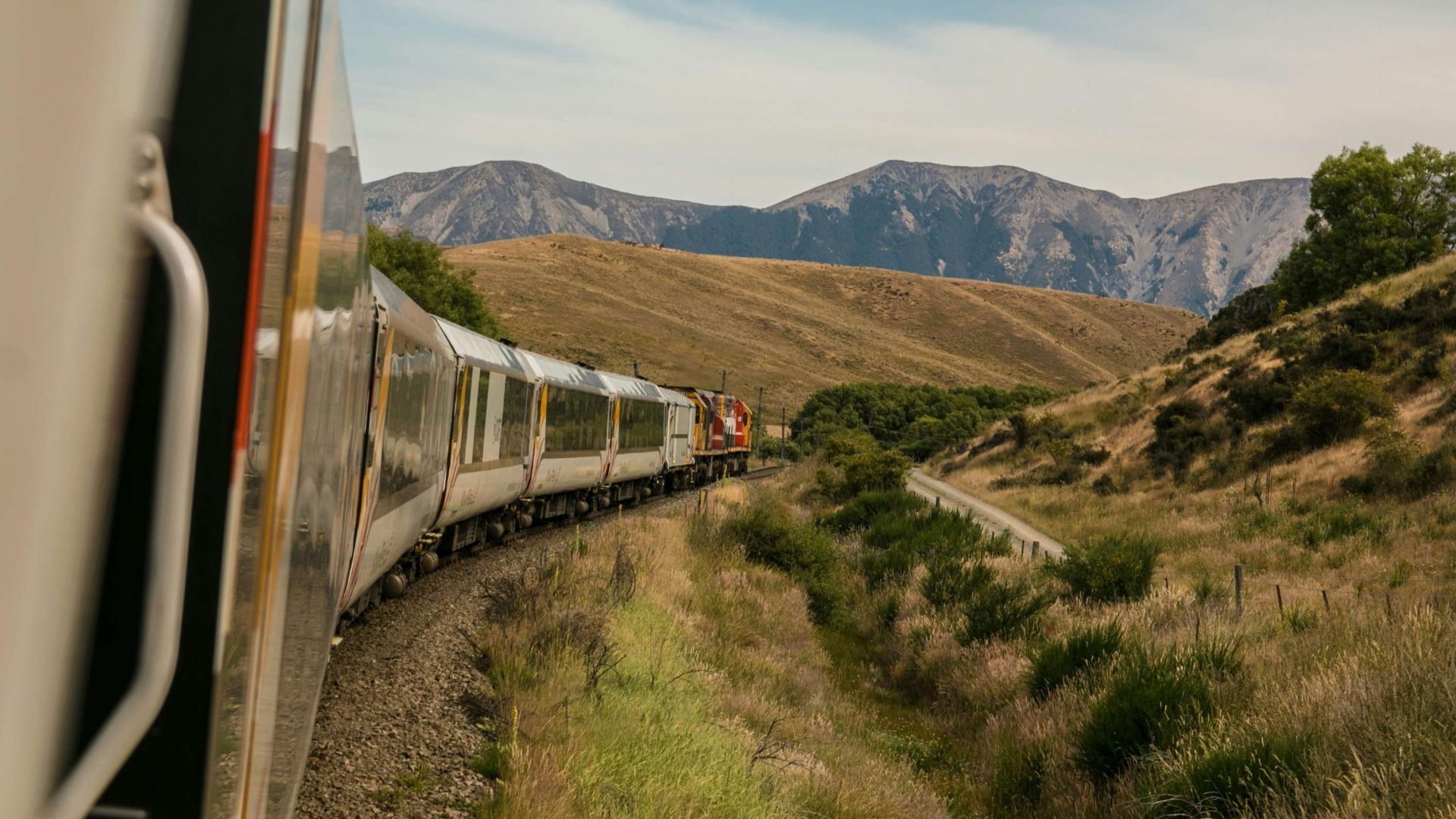 A train curves around a bend, with mountains in the background.