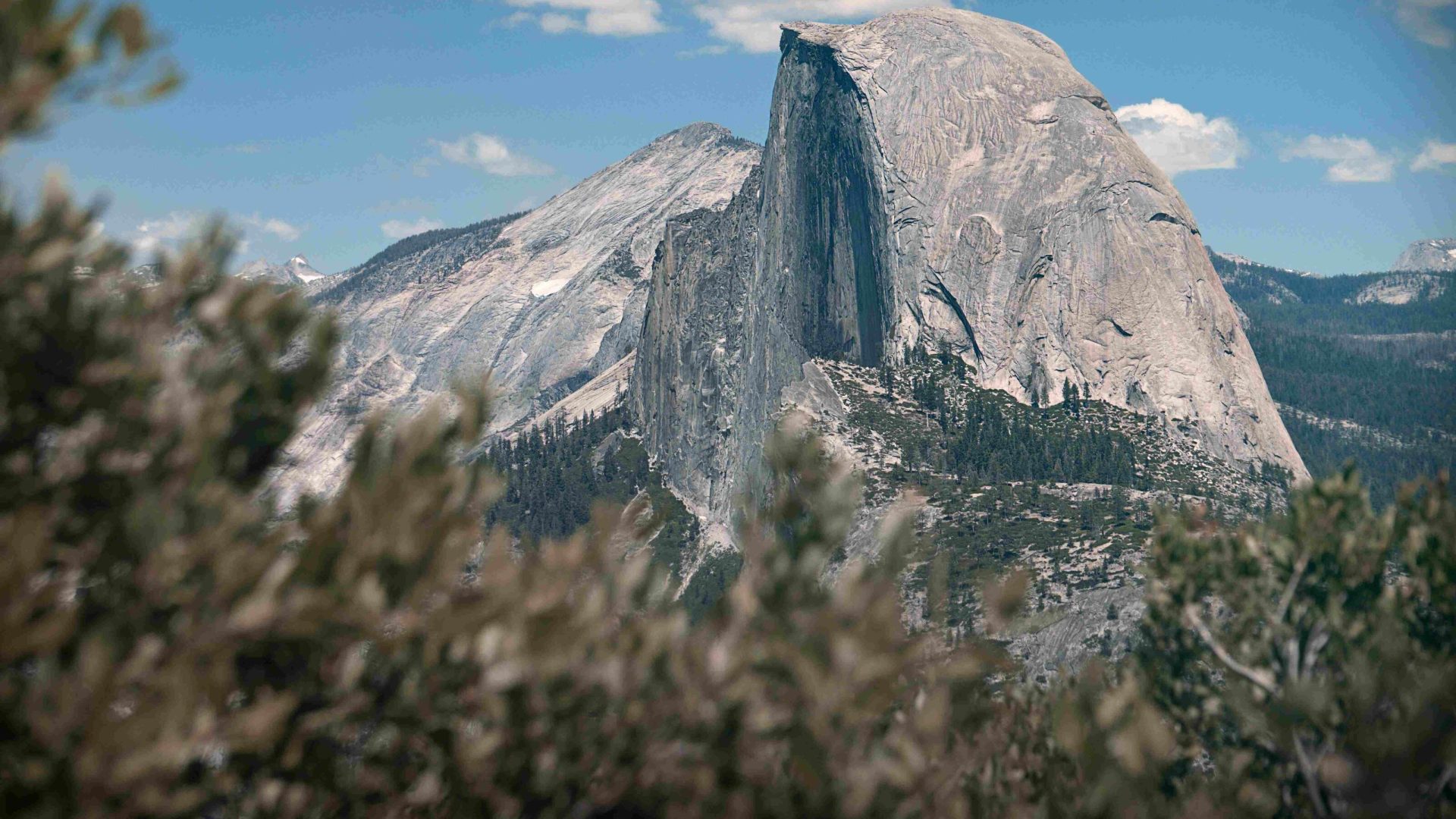 A view of Half Dome in Yosemite National Park during the daytime, with blue skies.