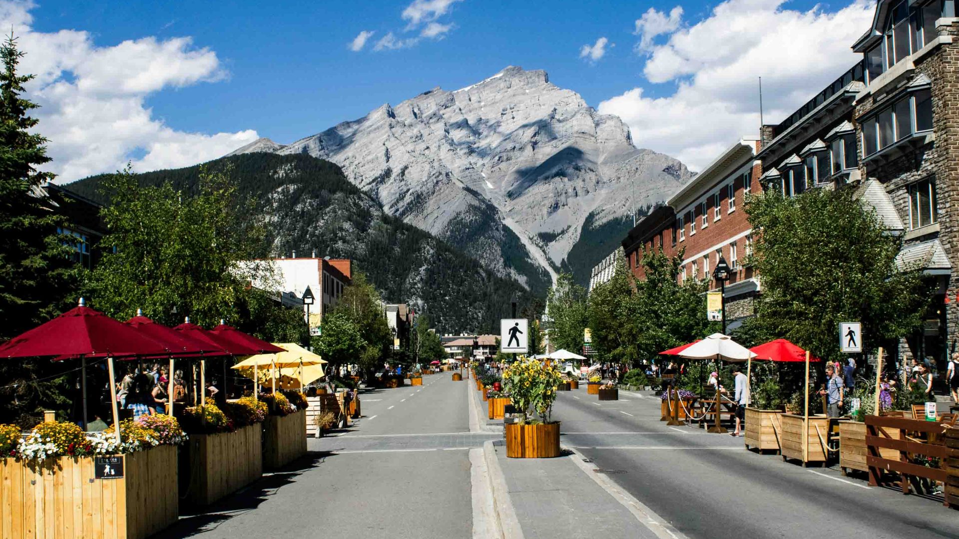 A village with outside seating and a mountain in the background.