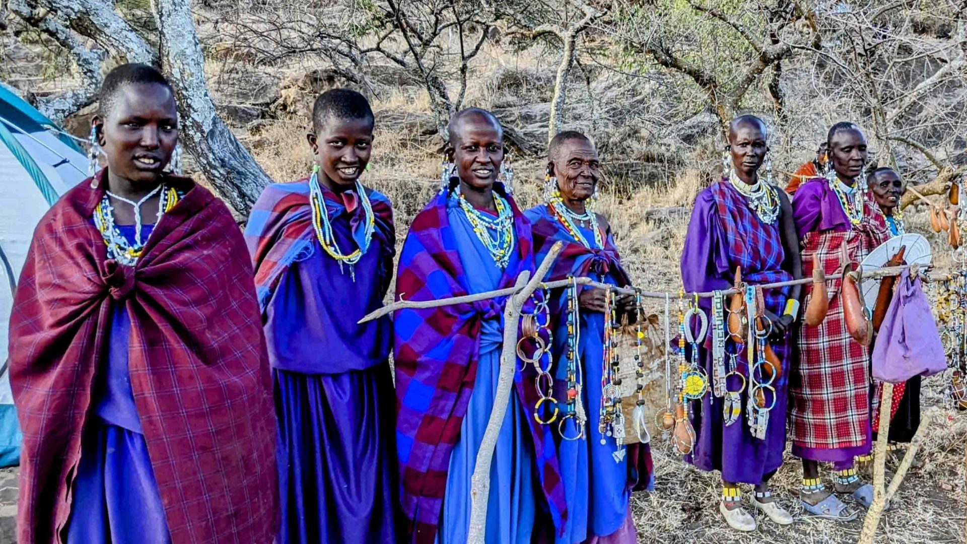 Maasai women hold out their jewellery.