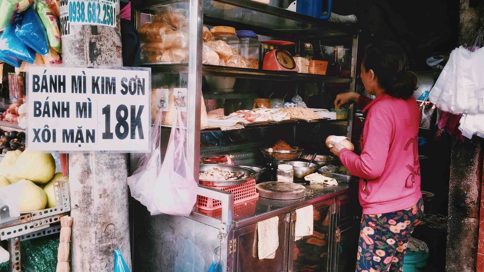 A woman sells bahn mi from her stall.