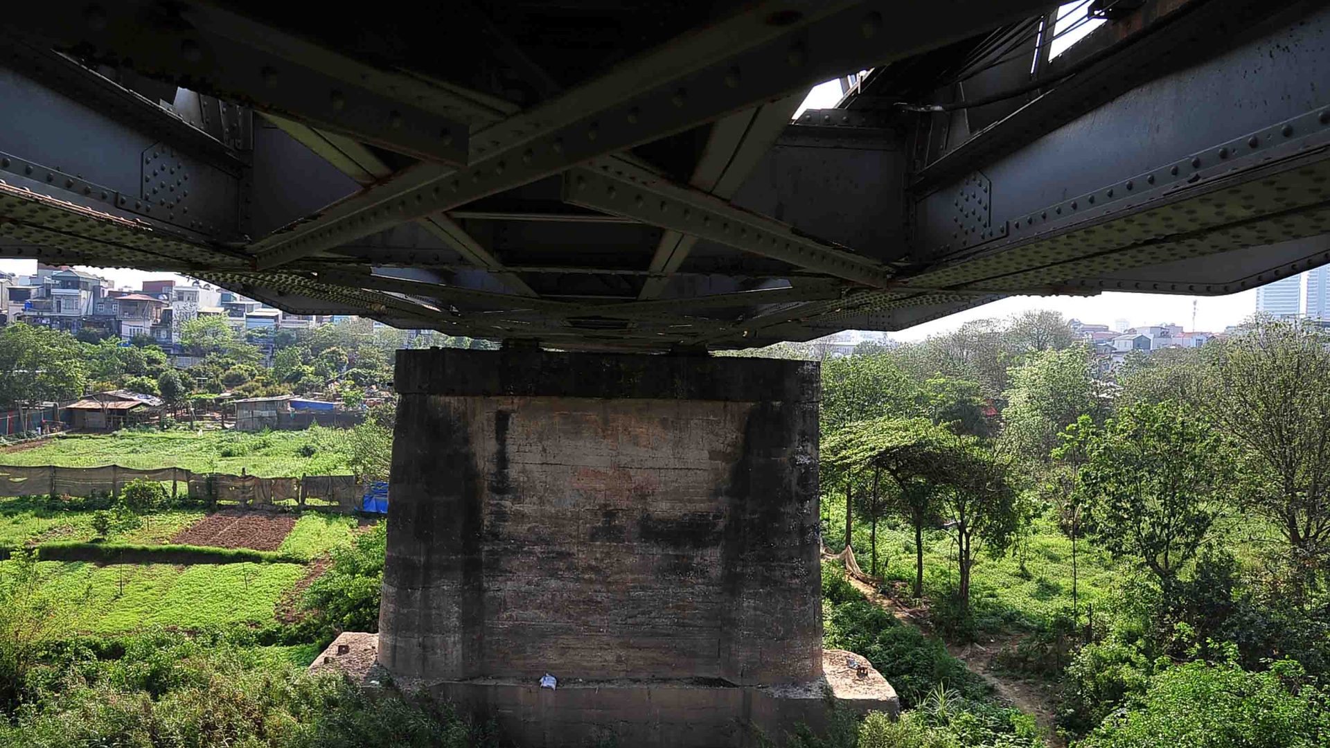 The under side of a bridge surrounded by trees.