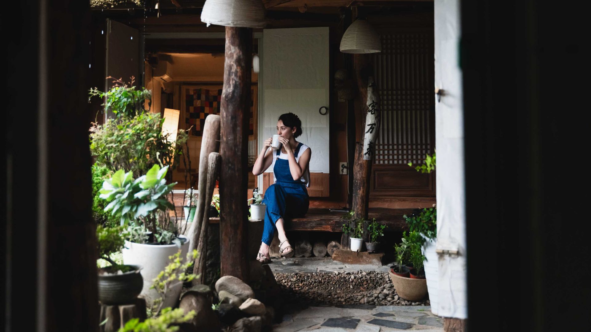 A woman relaxes with a cup of tea while seated in front of a building.