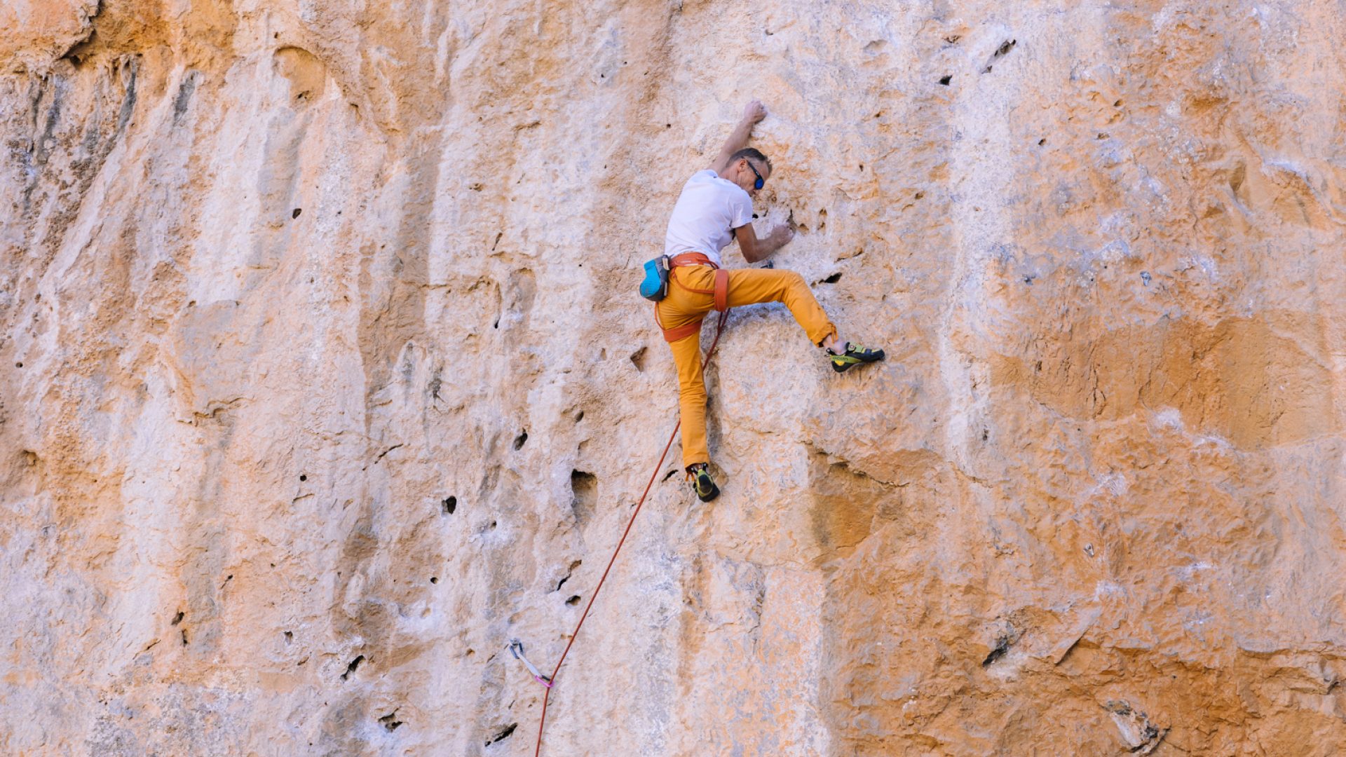 Climber in orange pants on huge rock wall