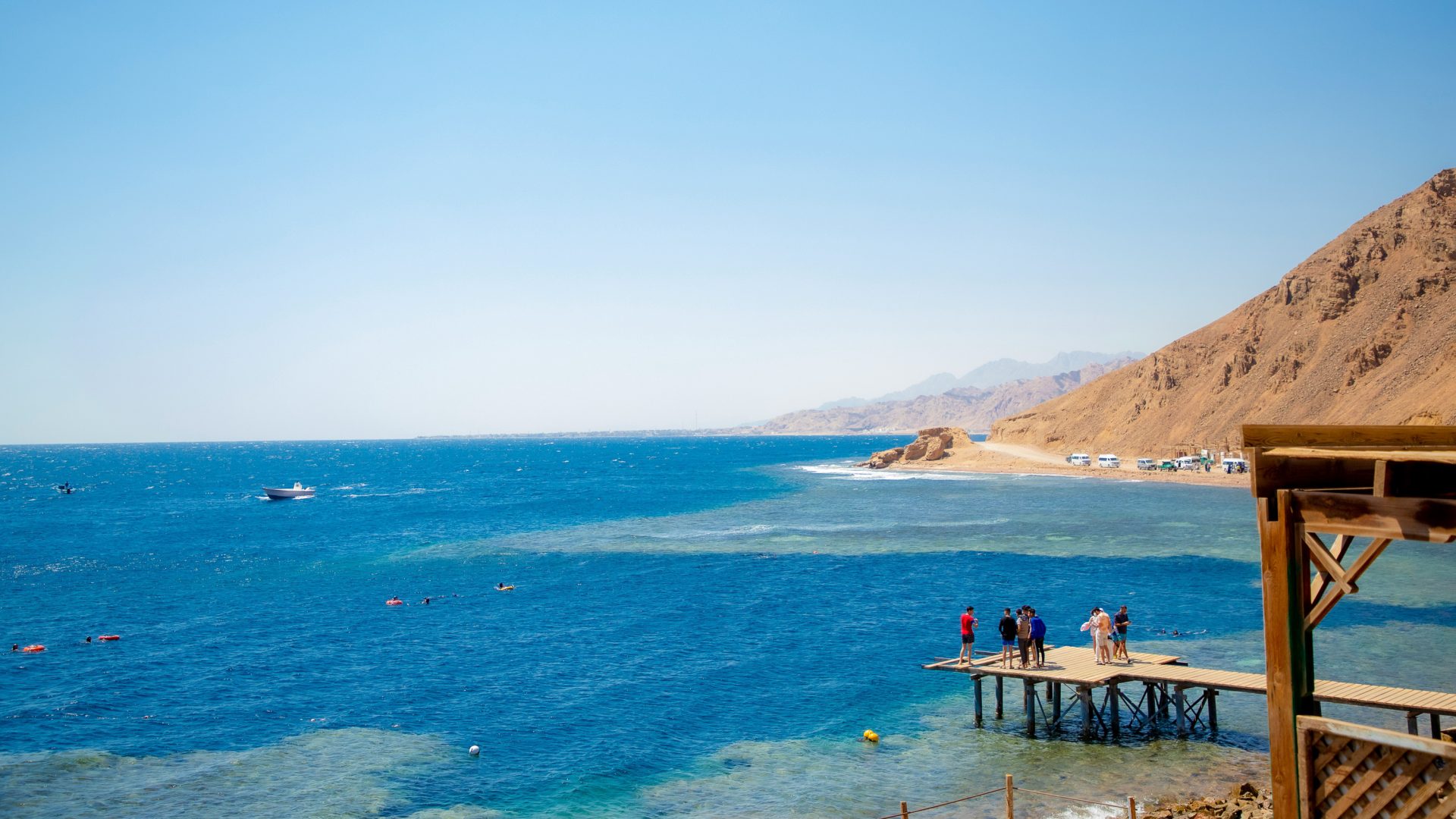 People stand and look out at blue water.