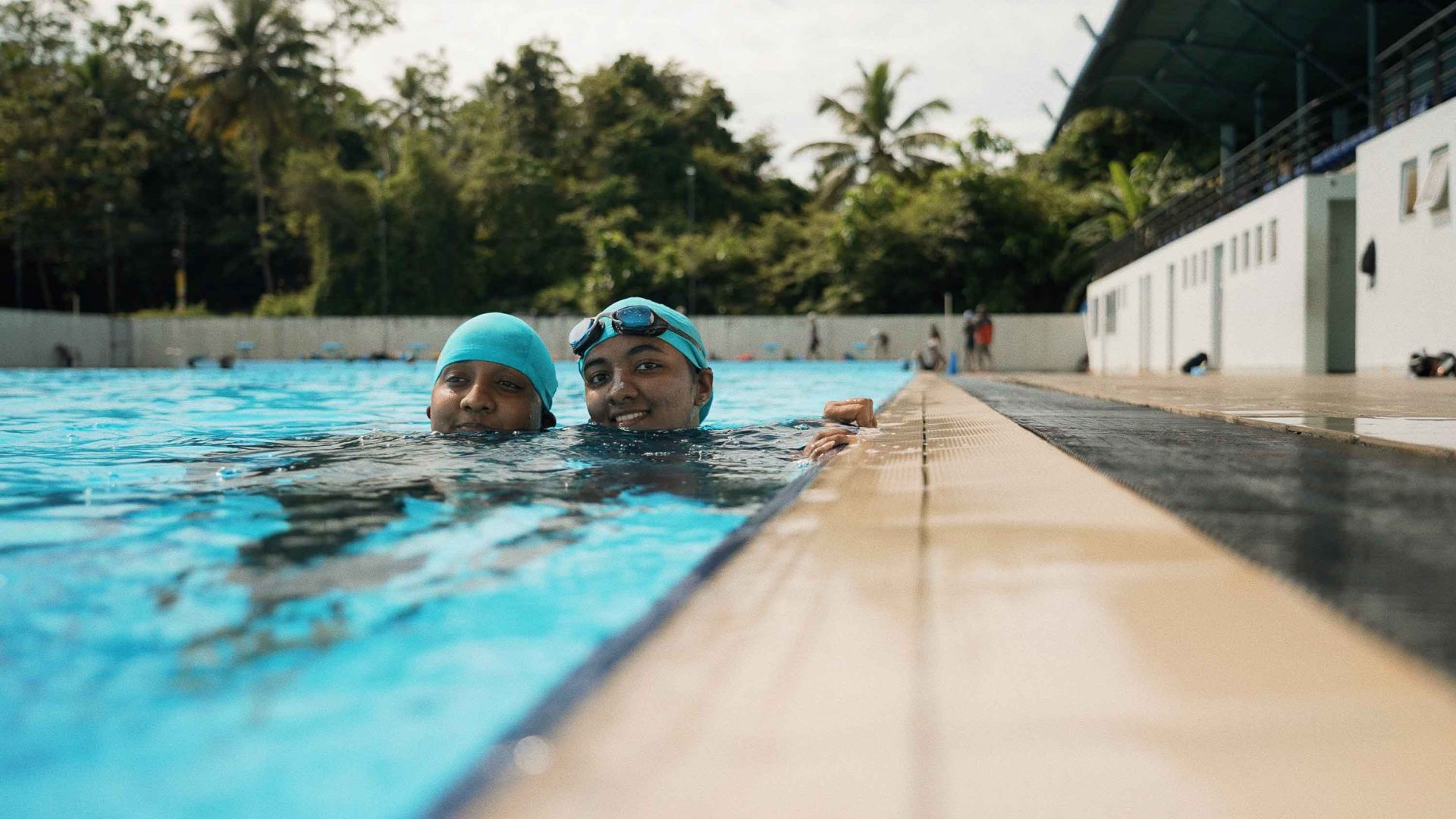 Two girls smile in the swimming pool.