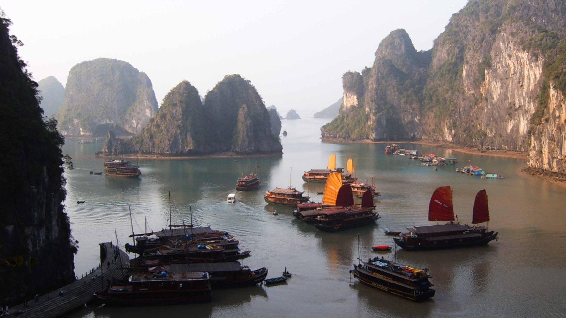 Looking down at several boats in the water, surrounded by limestone rocky outcrops.