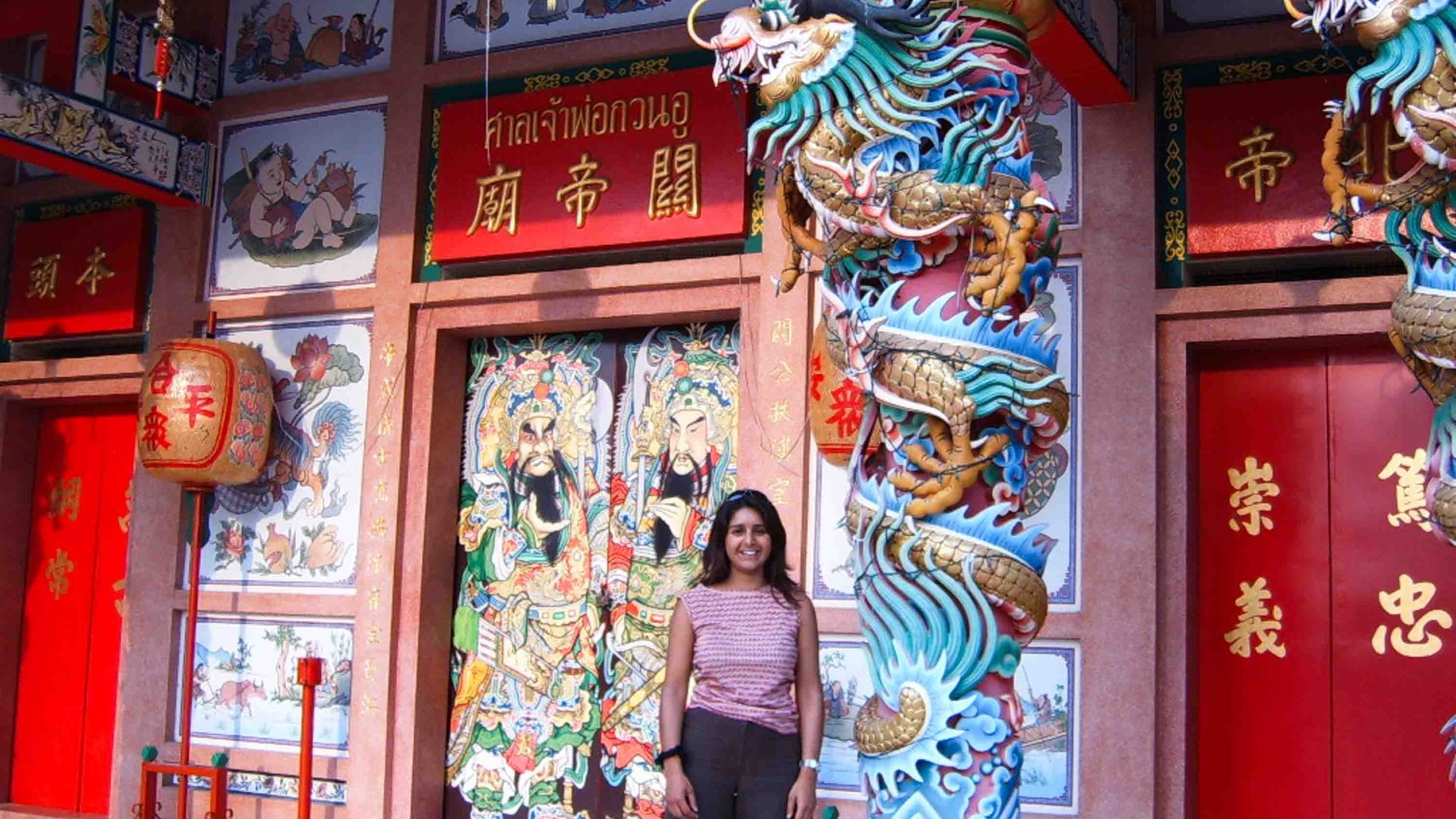 A woman stands in front of a colorful temple.