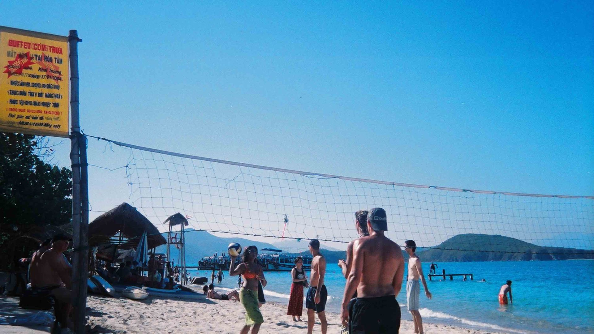 A group of people play volleyball on a beach.