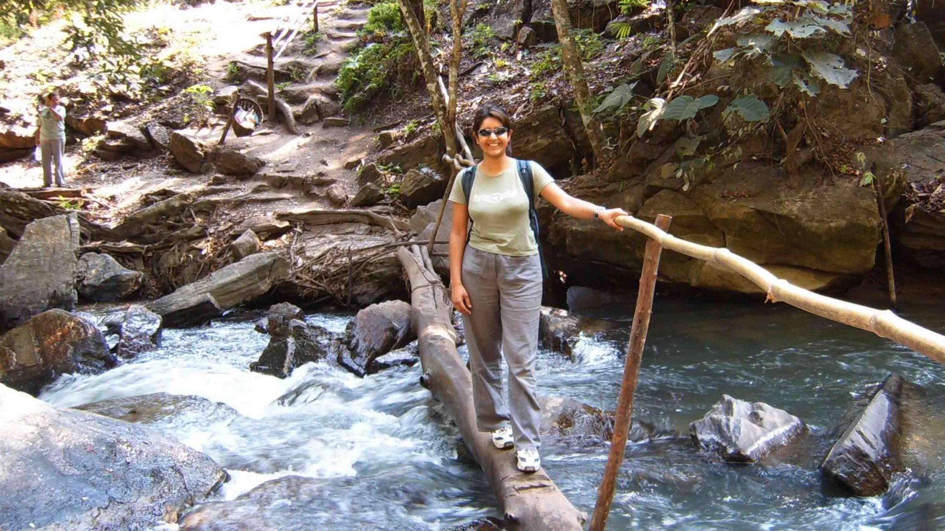 A woman crosses a bridge that is over a river.