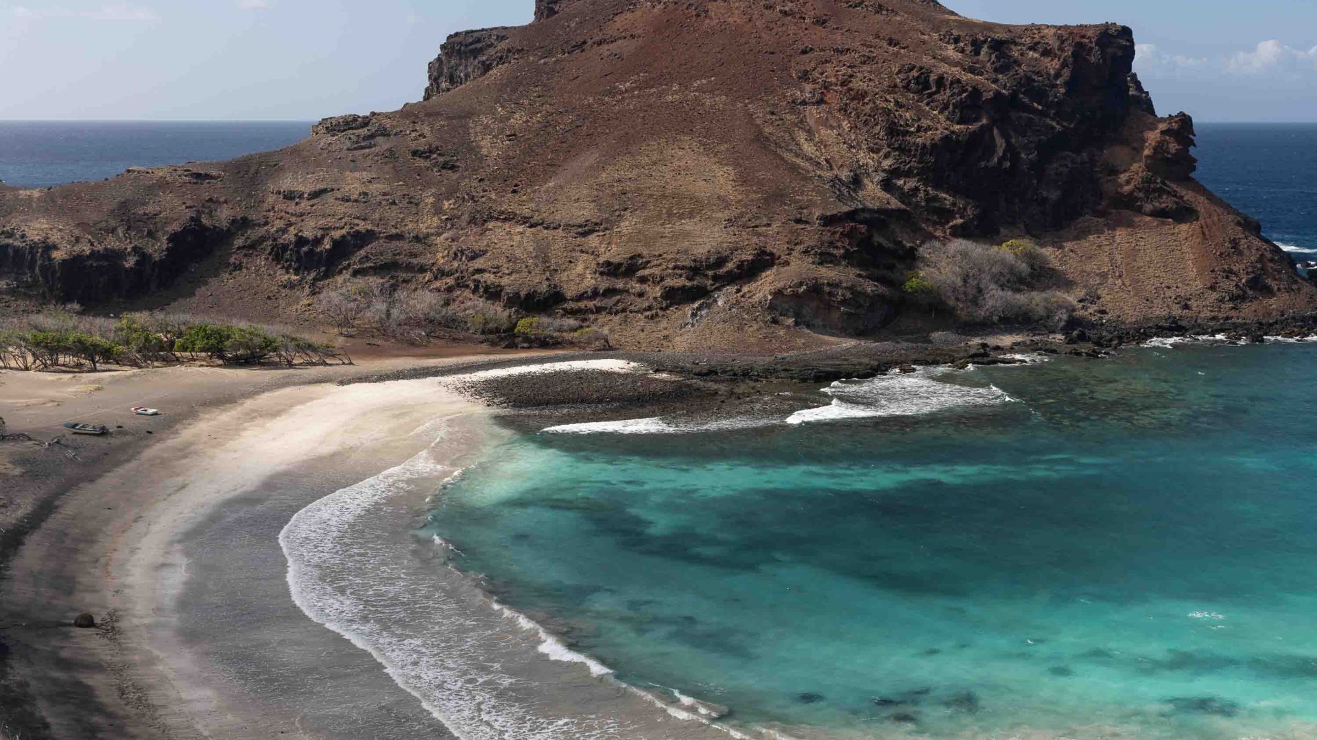 Turquoise water leads to a beach with rocks on it.