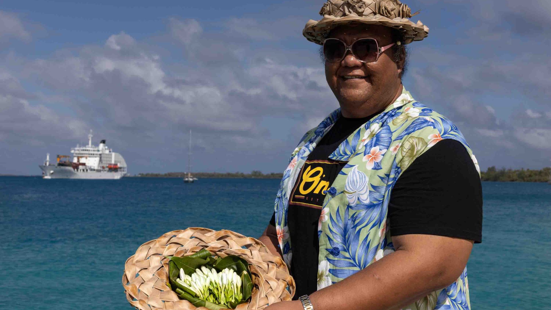 A man holds out a basket of flowers to welcome guests.