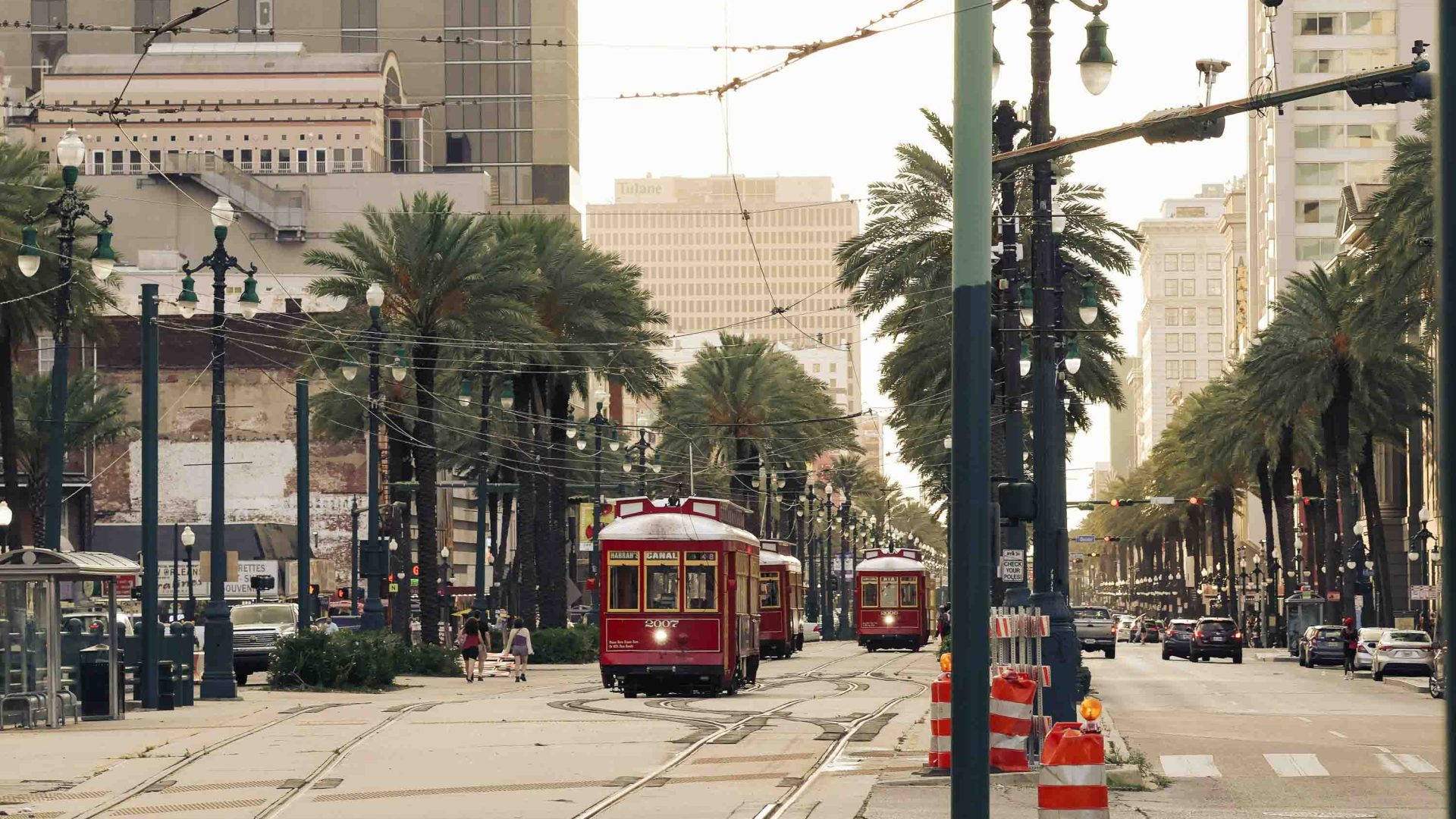 A red tram makes its way down a city street.