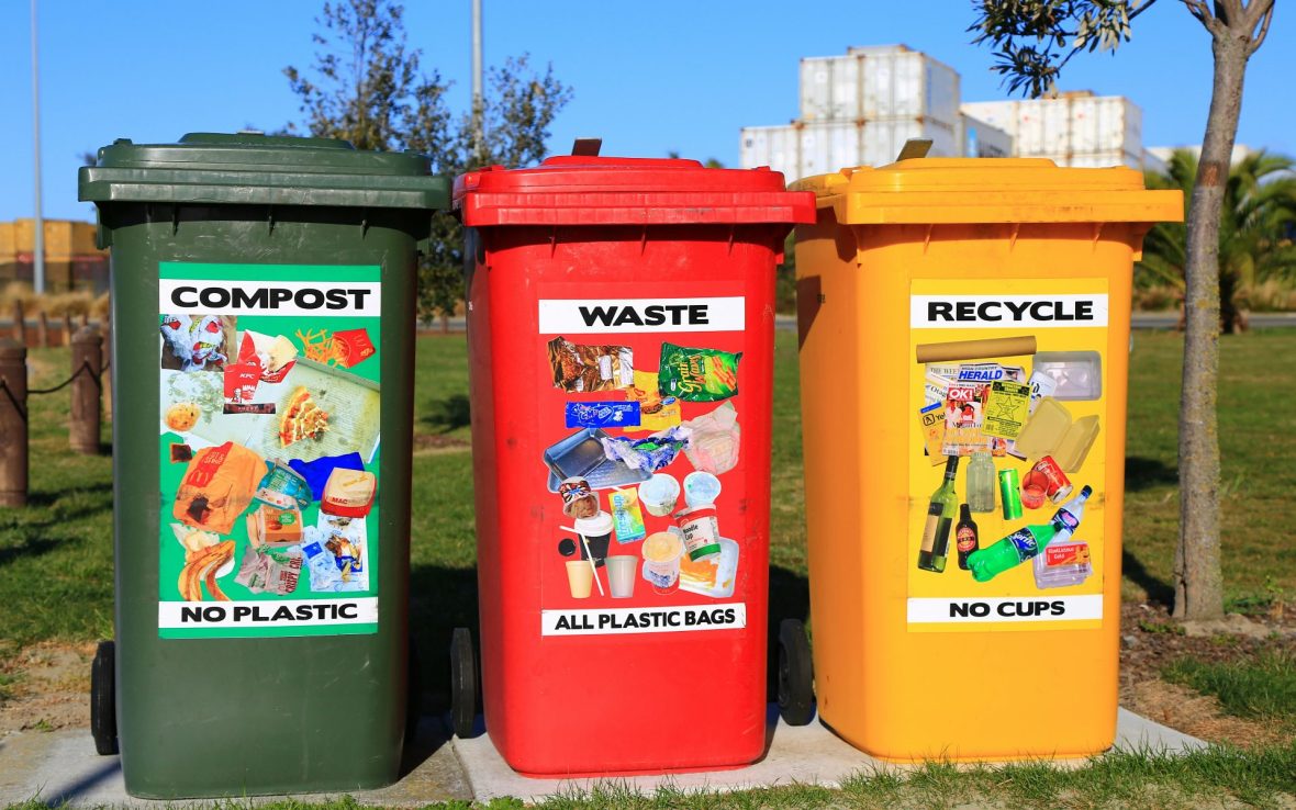 Three recycling bins, green, red and yellow, outside a house