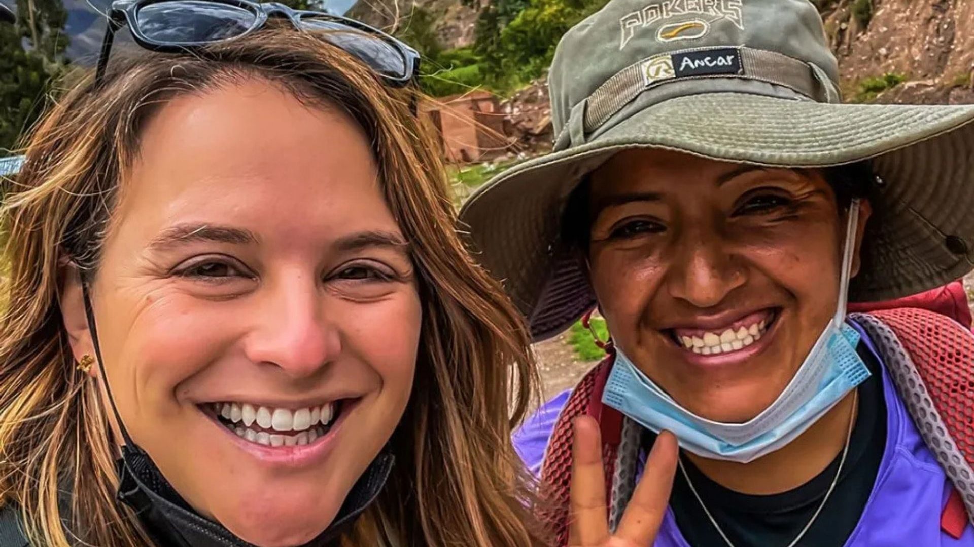 Two women, a traveler and a Peruvian guide, smiling to camera