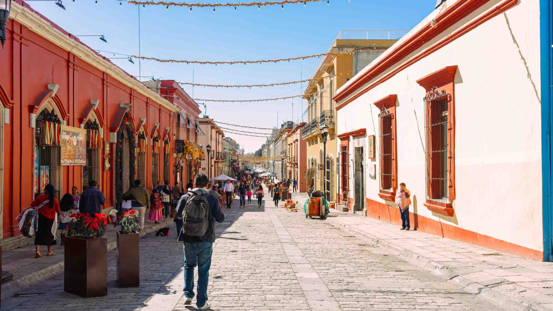 People walking in a street with terracotta coloured houses.