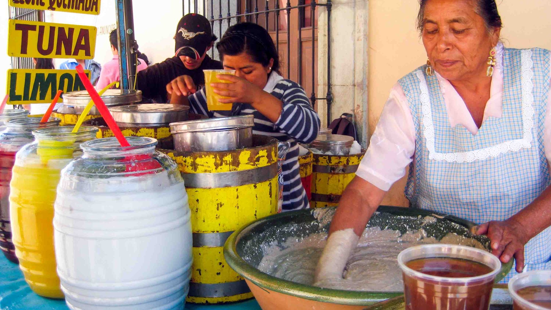 Women prepare a white coloured drink in a big bowl.