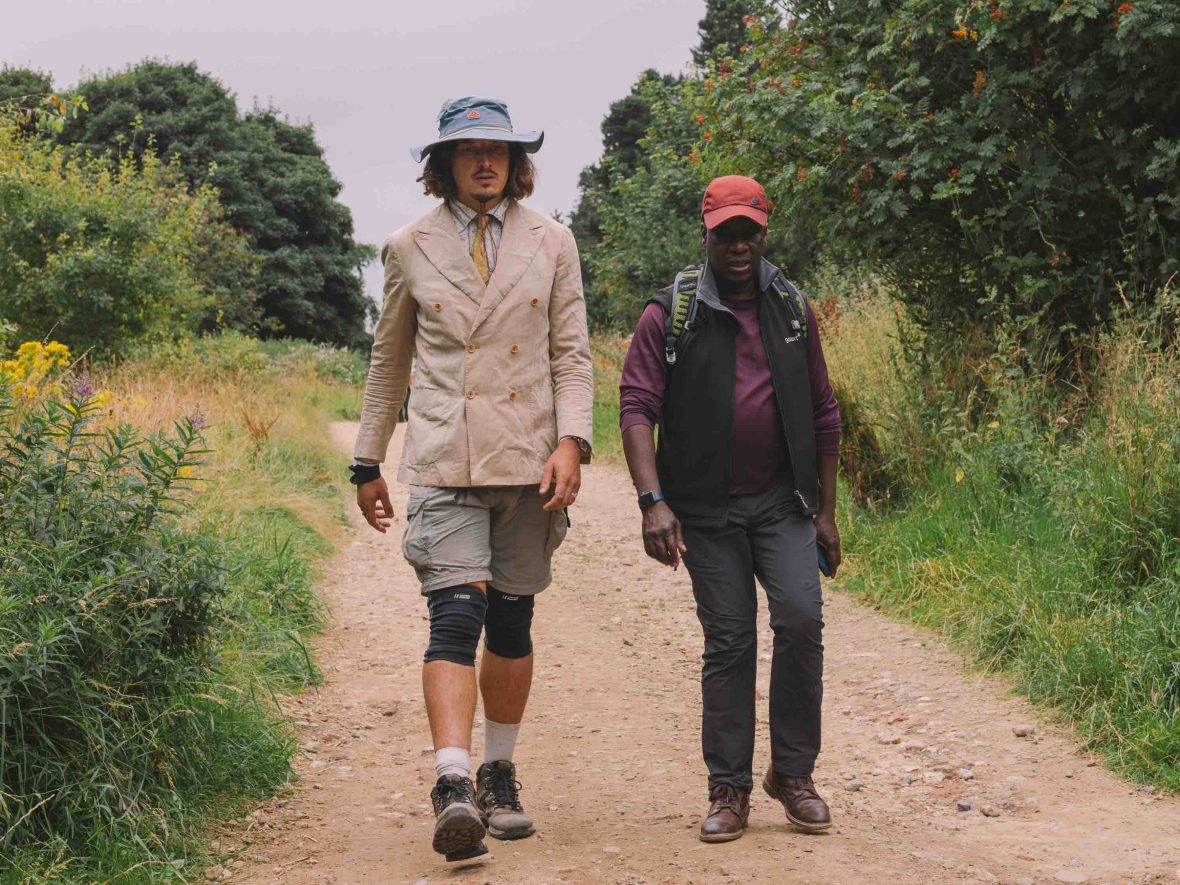 Two men walk along a trail talking together.