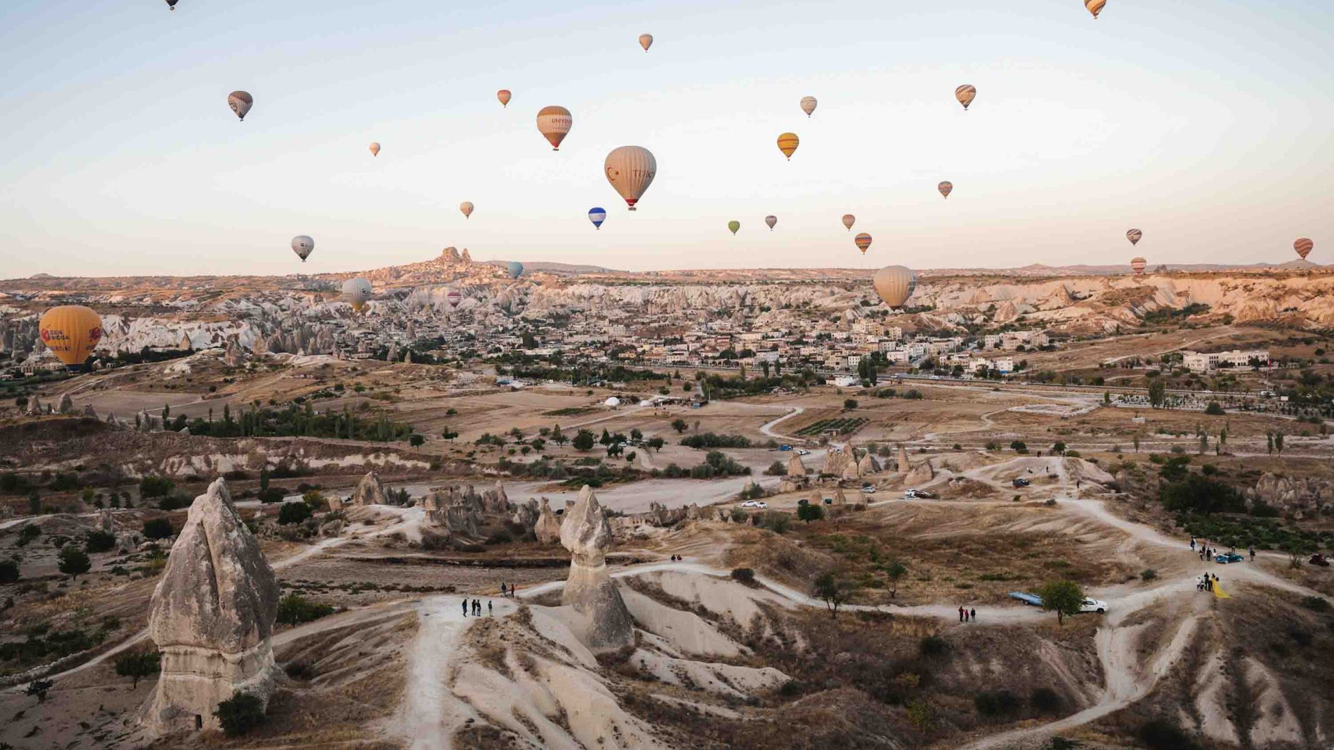 Hot air balloons fly in the air above the fairy chimneys and other rock formations.