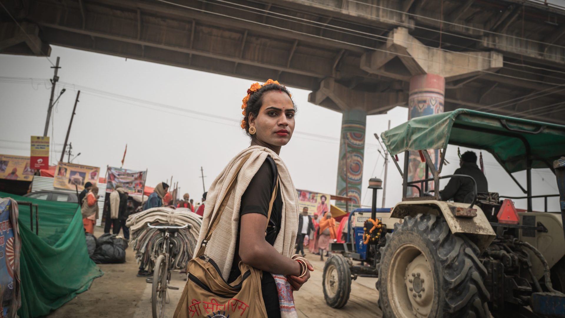 A hijras person walks beneath bridge.