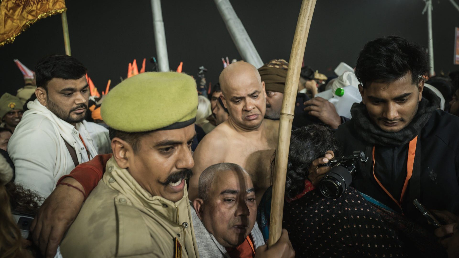 An older man is helped by Indian police through the crowd