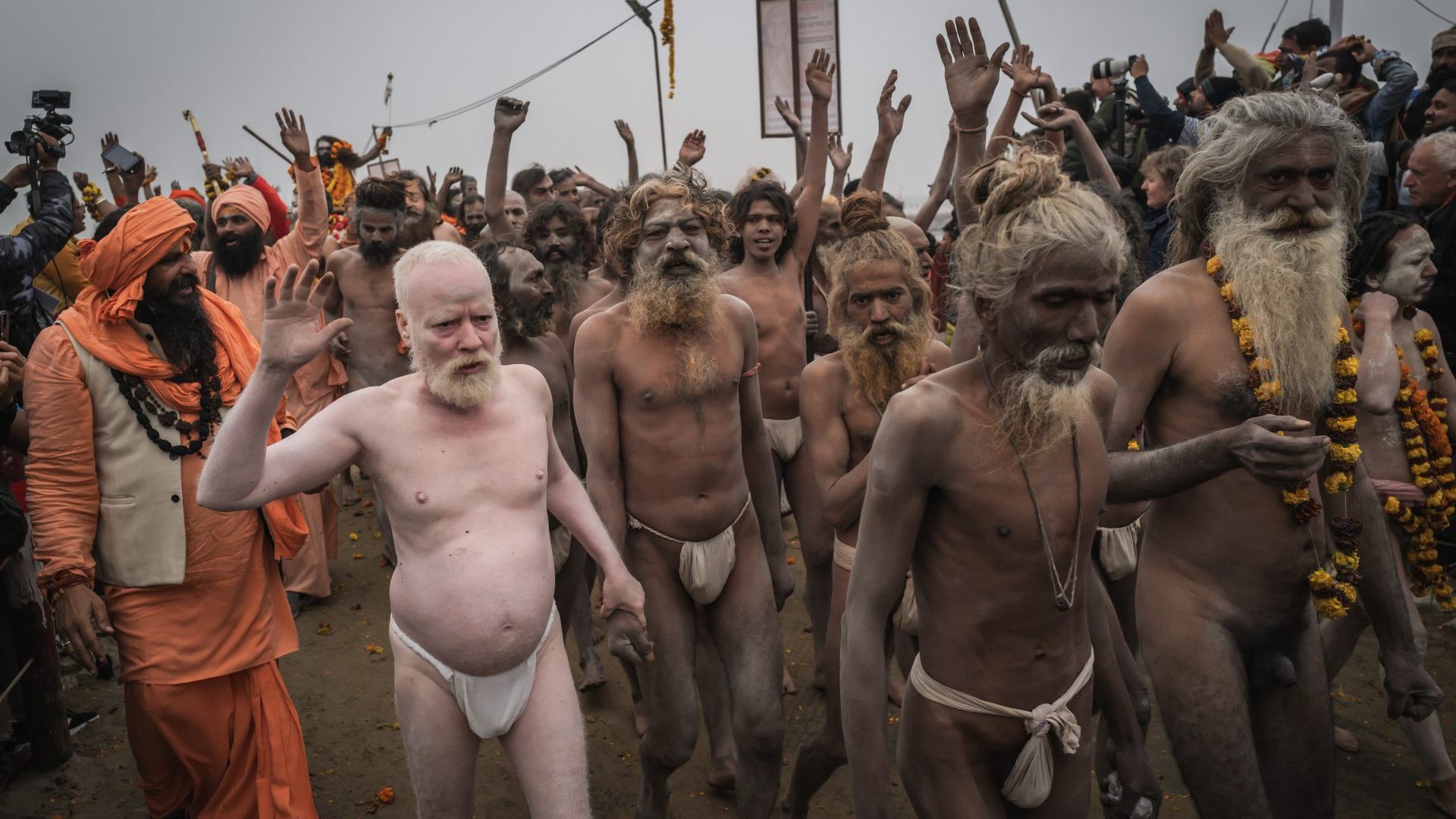 Holy men covered in ash walk to the water