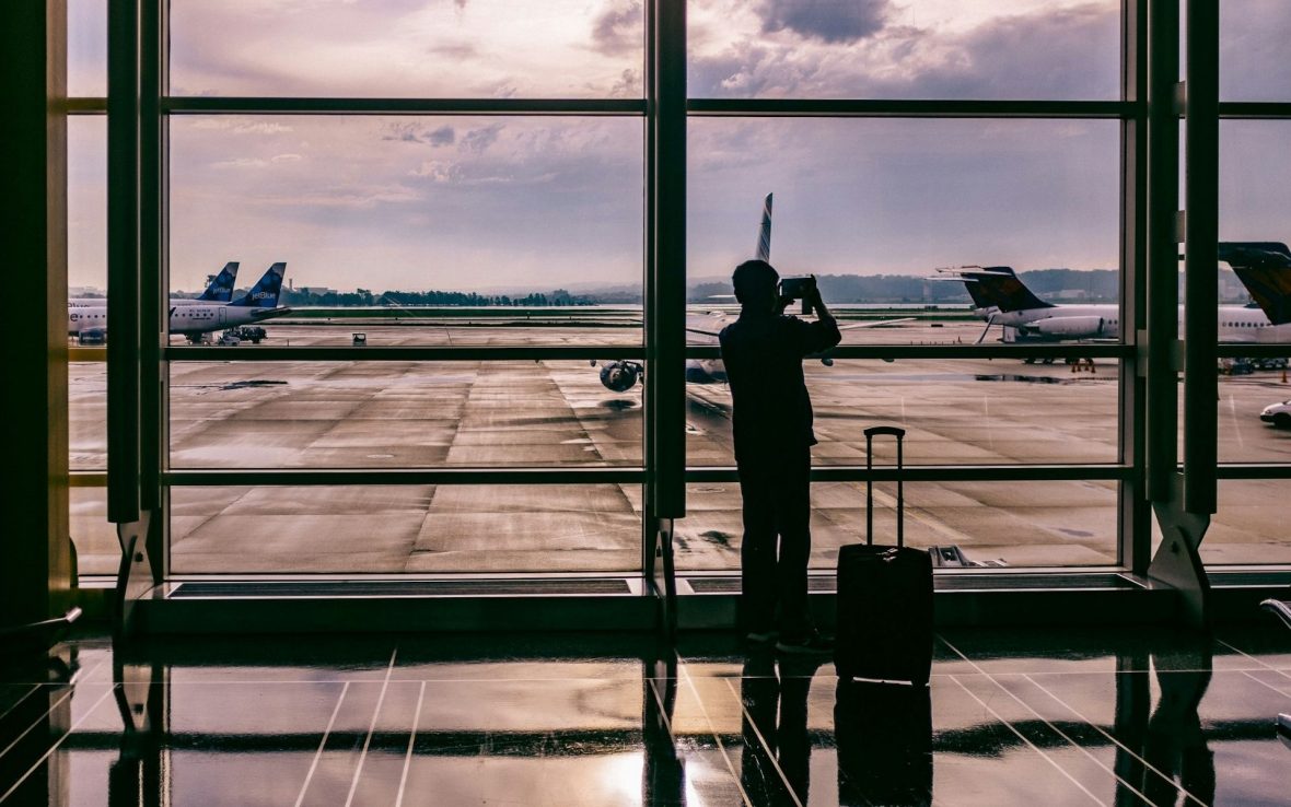 A traveler watches the planes from a large airport window