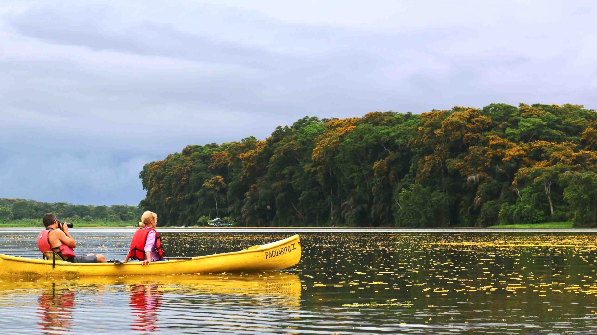 Two people on a yellow canoe in a river.