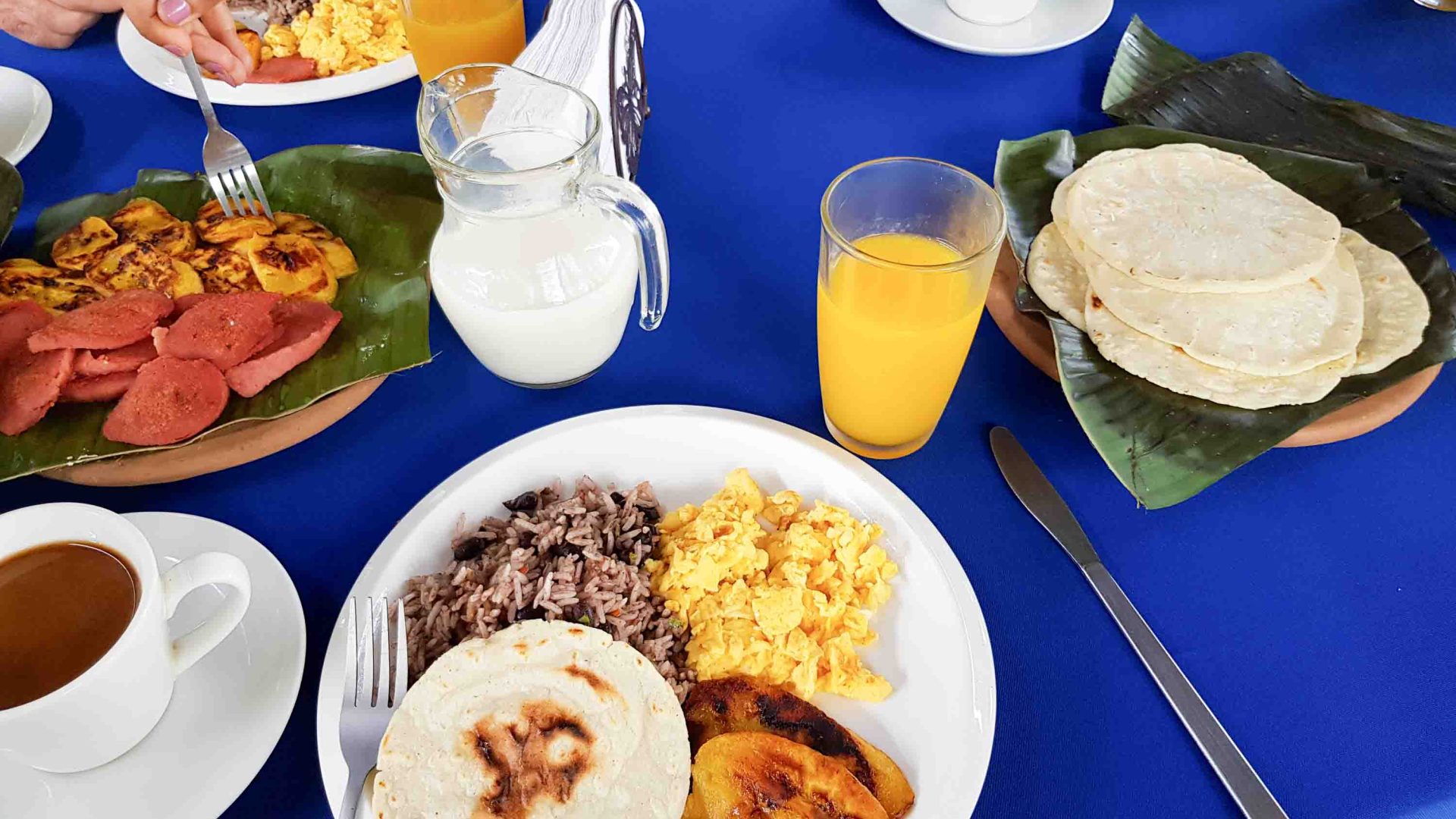 A breakfast of rice, eggs, plantains, juice and other items.