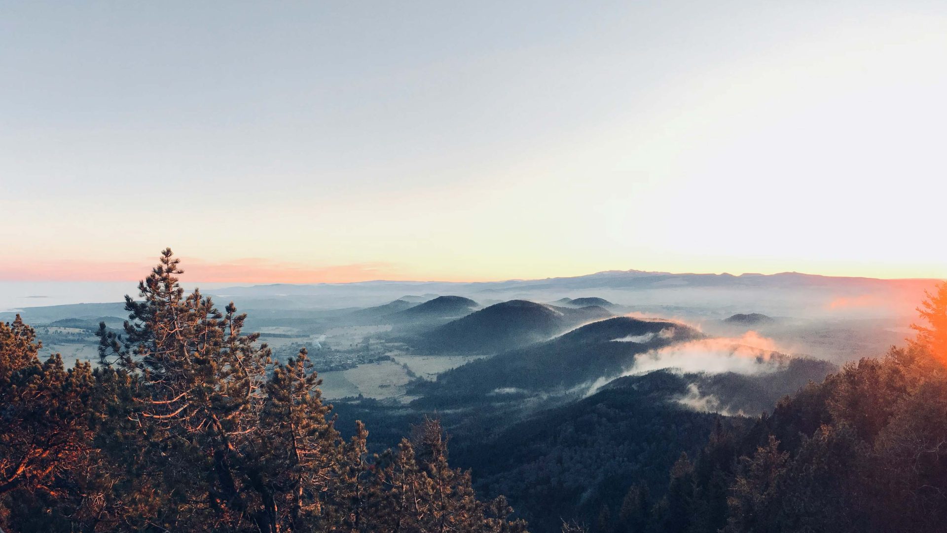 Clouds rest on mountains in soft orange light.