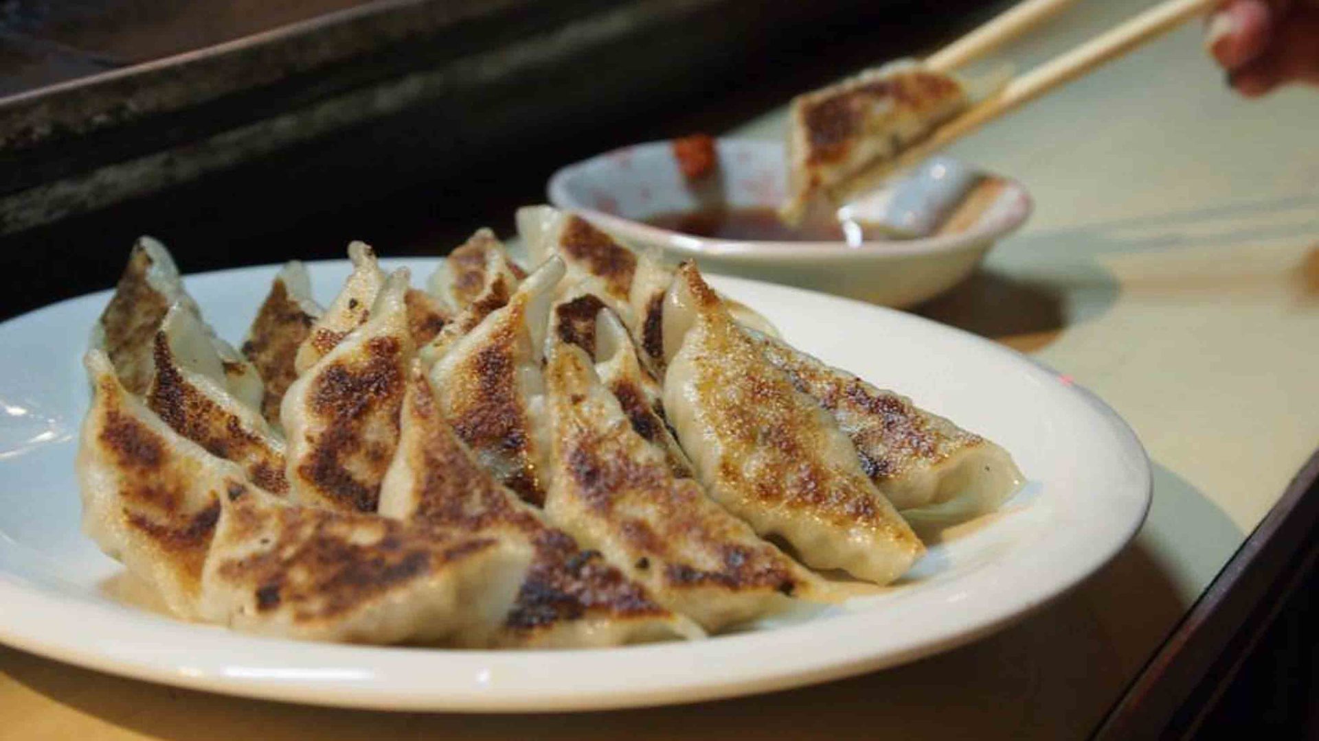 A plate of gyoza and some dipping sauce.