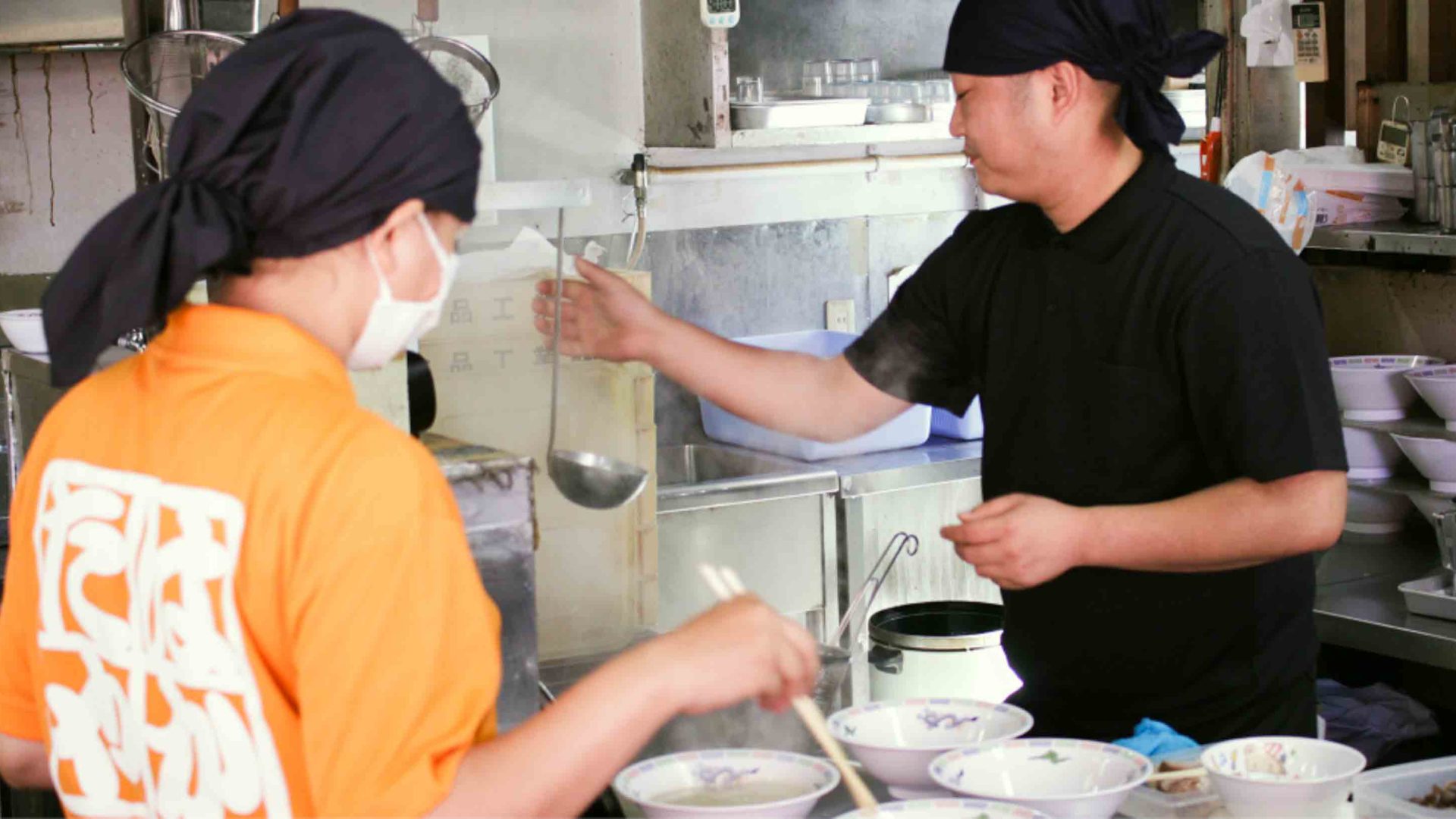 Chefs in a kitchen with empty bowls in front of them.