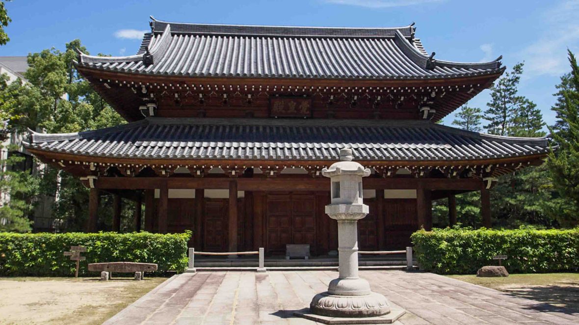 The exterior of a temple with curved roof and brown intricate walls.