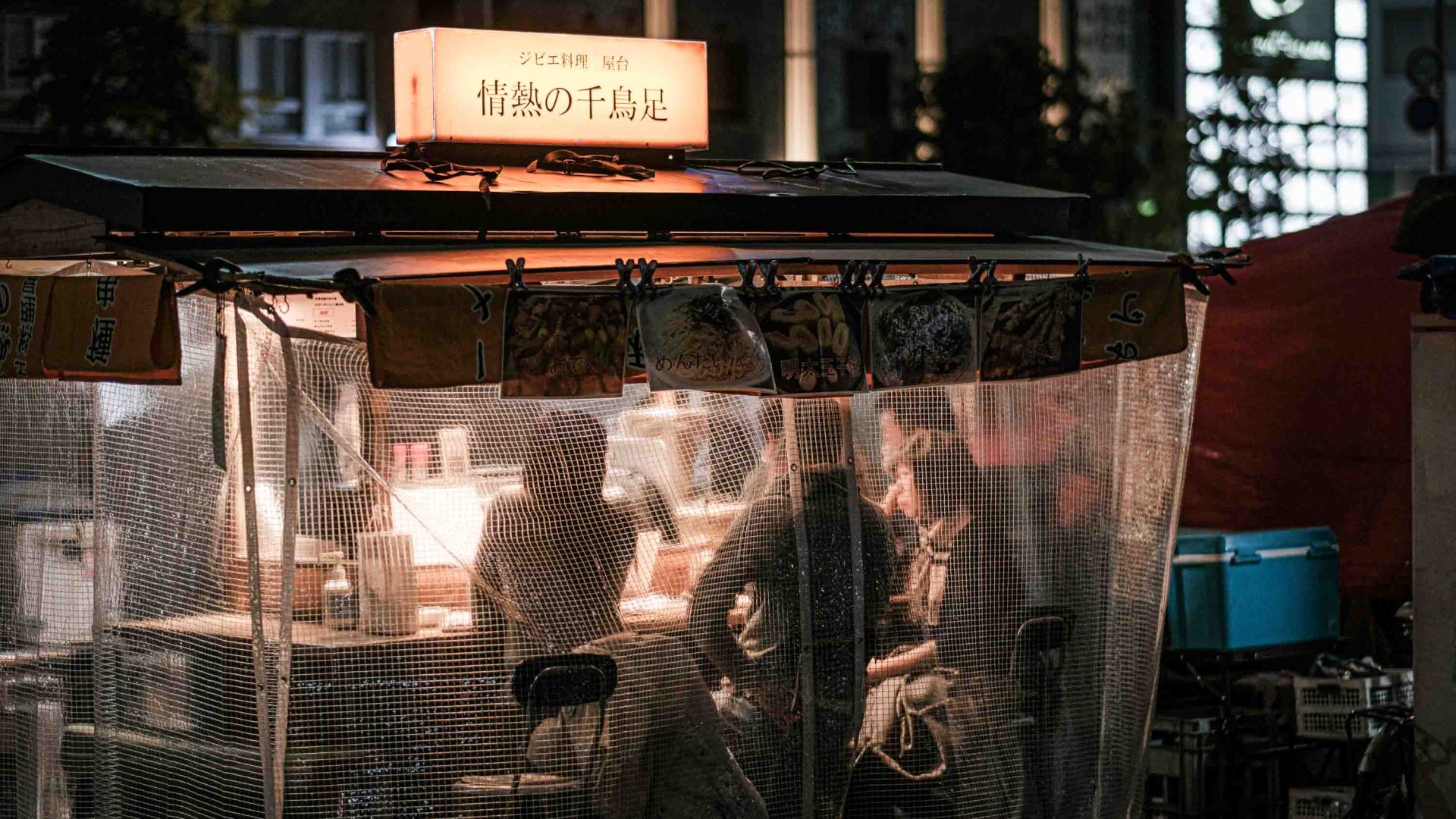 People inside a yatai with the plastic cover drawn down.