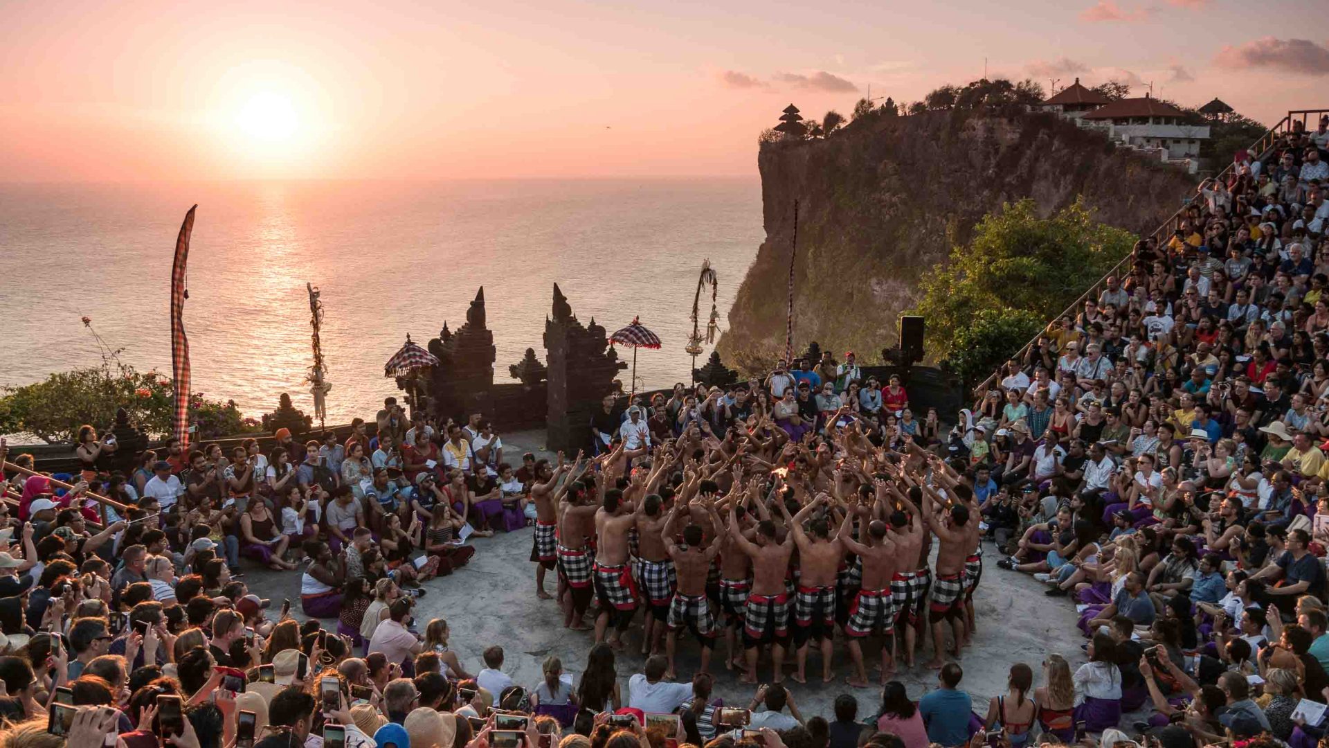 Tourists watch a performance by dancers at the coast.