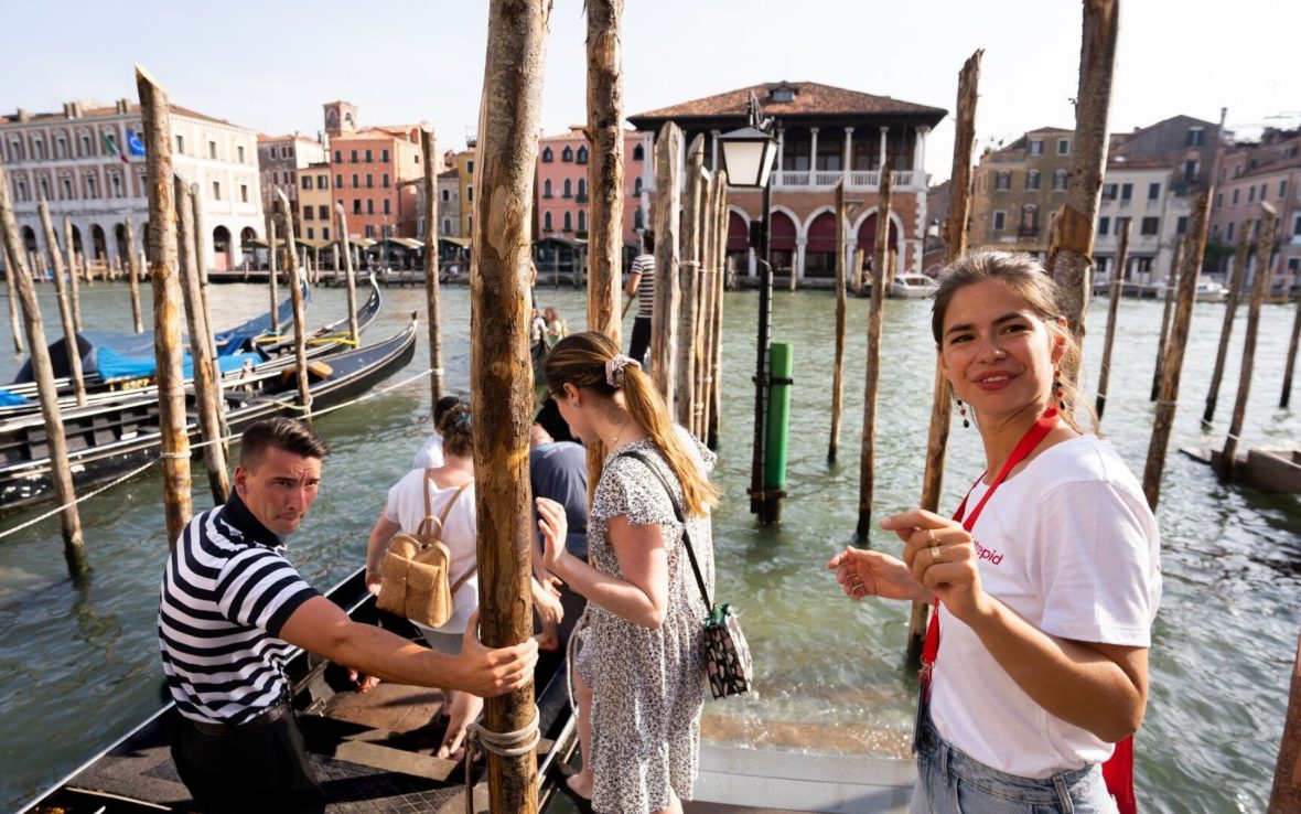 A guide smiles to camera as she and her group embark a boat in Venice