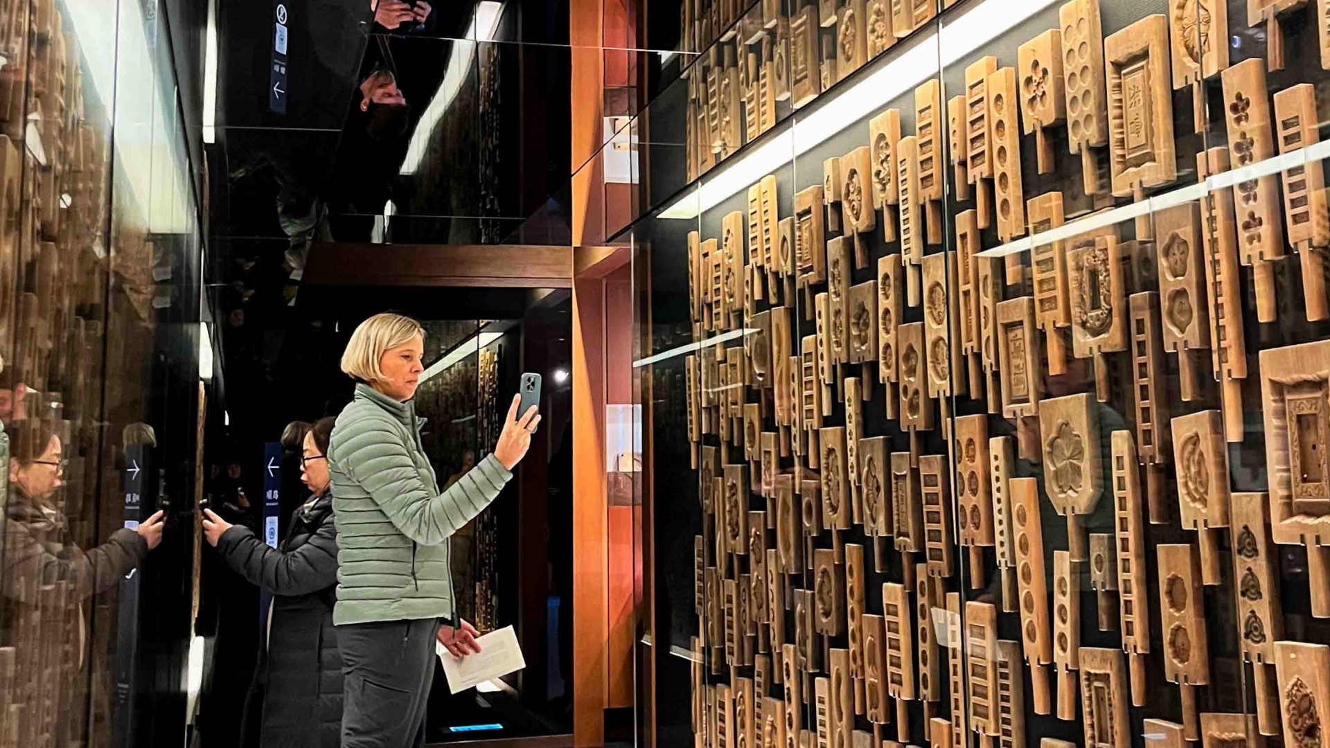 A traveler takes photos on her phone of a museum display.