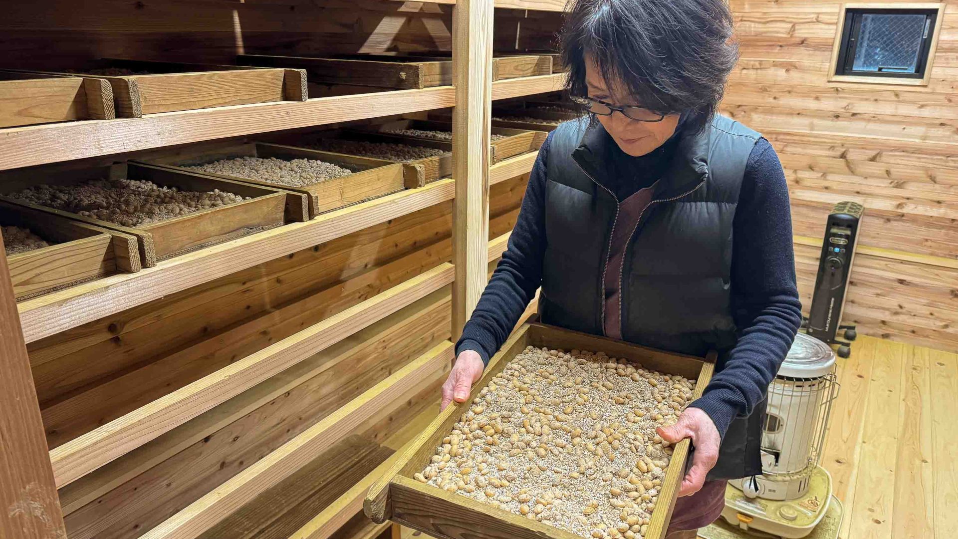 A woman holds a tray of soy beans.