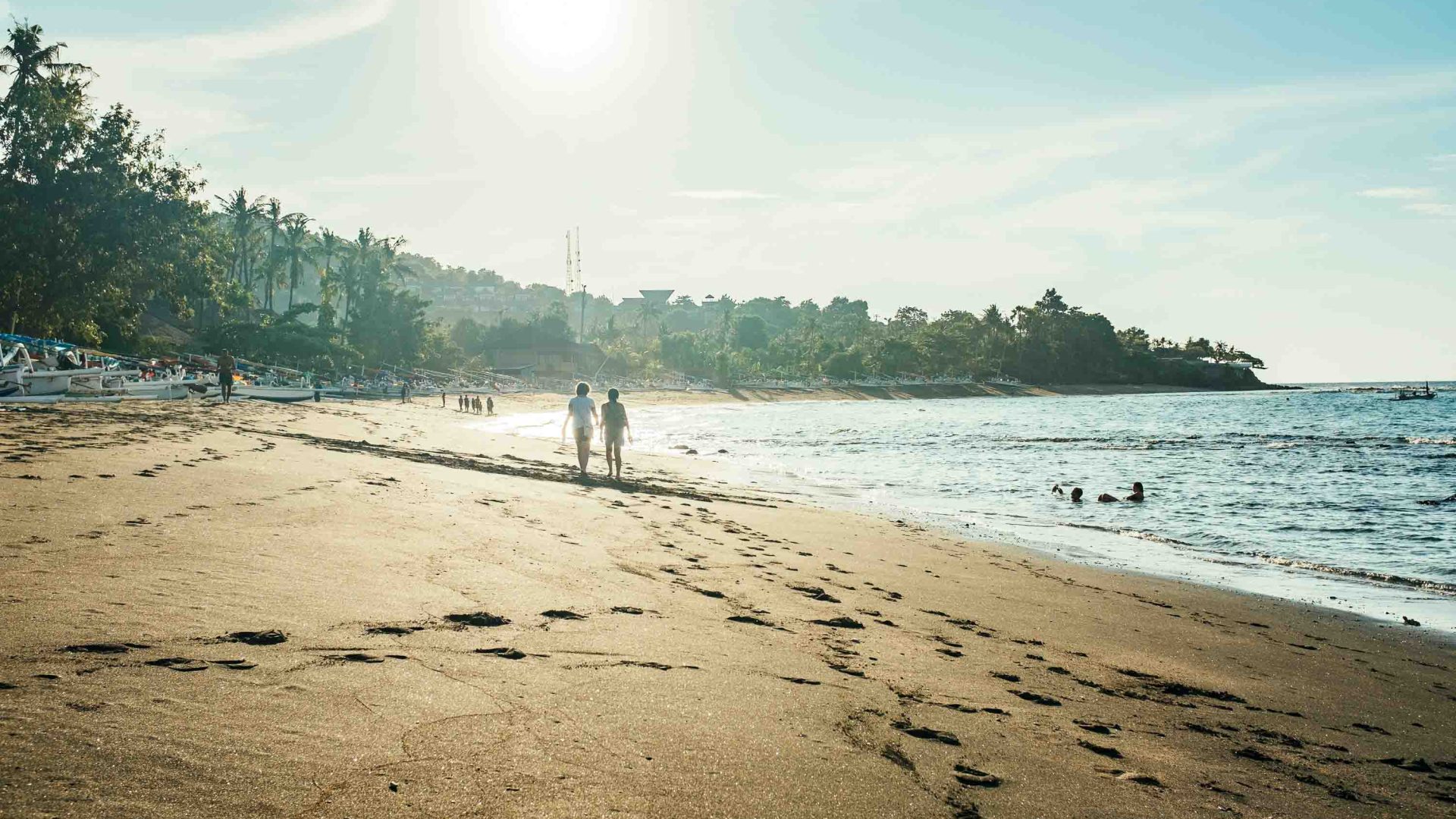 A couple walk along the sand of a beach.